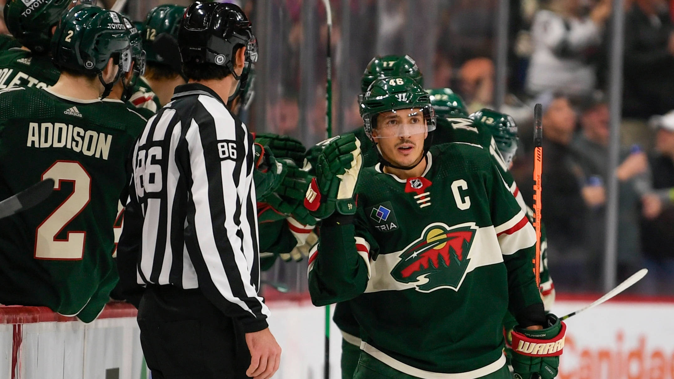 hockey 桌布 壁紙 — 穿著綠色球衣的冰球球員在冰上激烈的比賽時刻與裁判對峙。