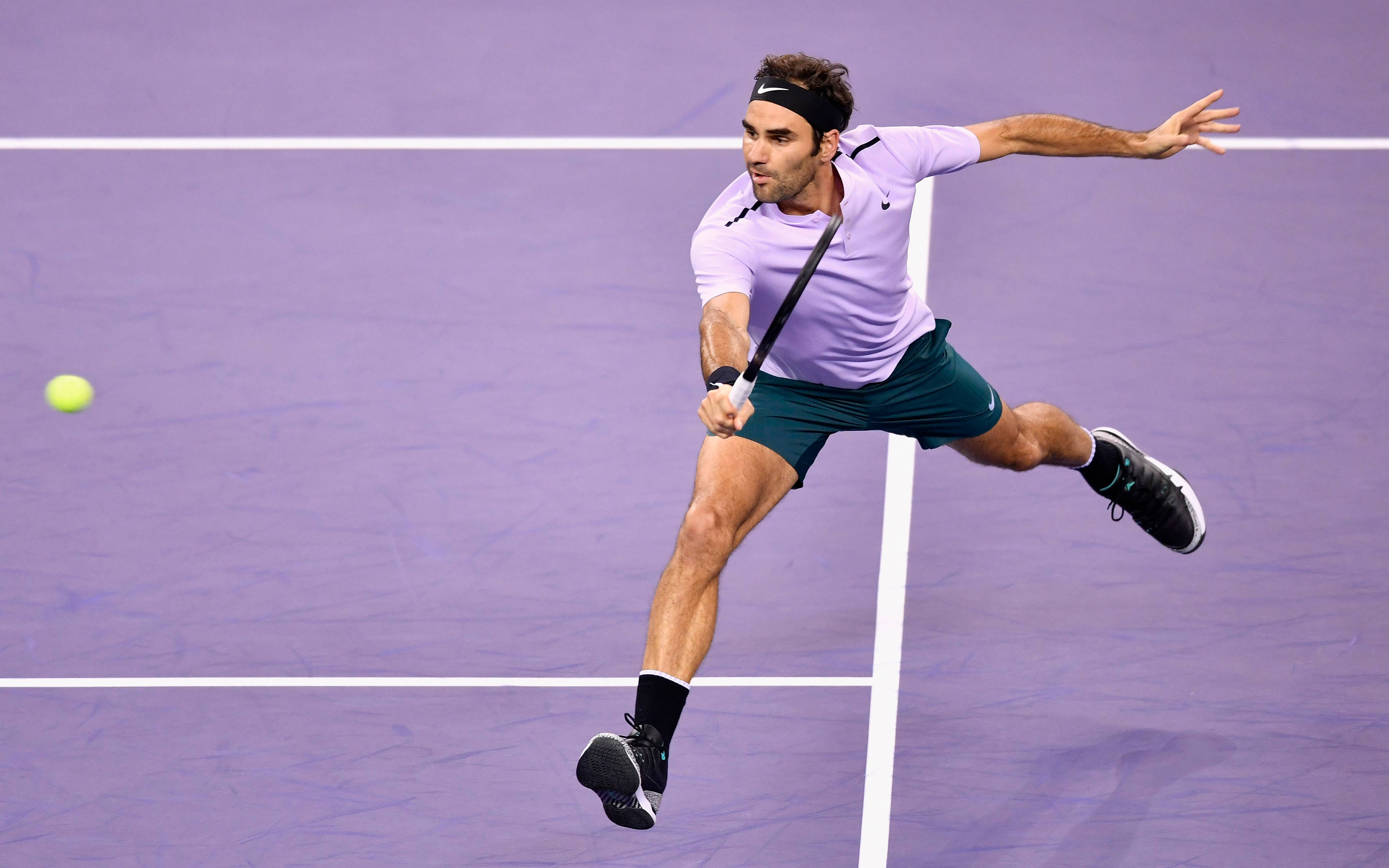 roger 桌布 壁紙 — 穿著薰衣草色襯衫的網球選手在紫色球場上向前猛衝，以強烈的專注力擊打黃色球。