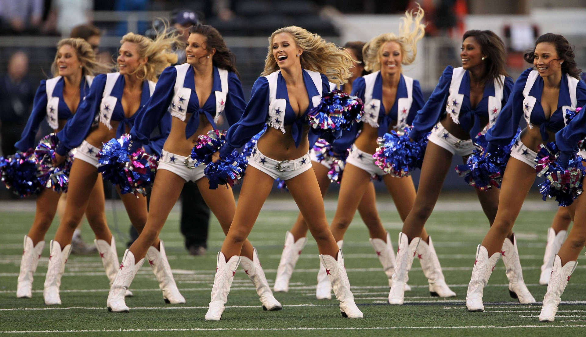Cheerleader 桌布 壁紙 — 穿著藍色星星制服和白色靴子的啦啦隊員在足球場上充滿活力地跳舞，彩球飛舞。