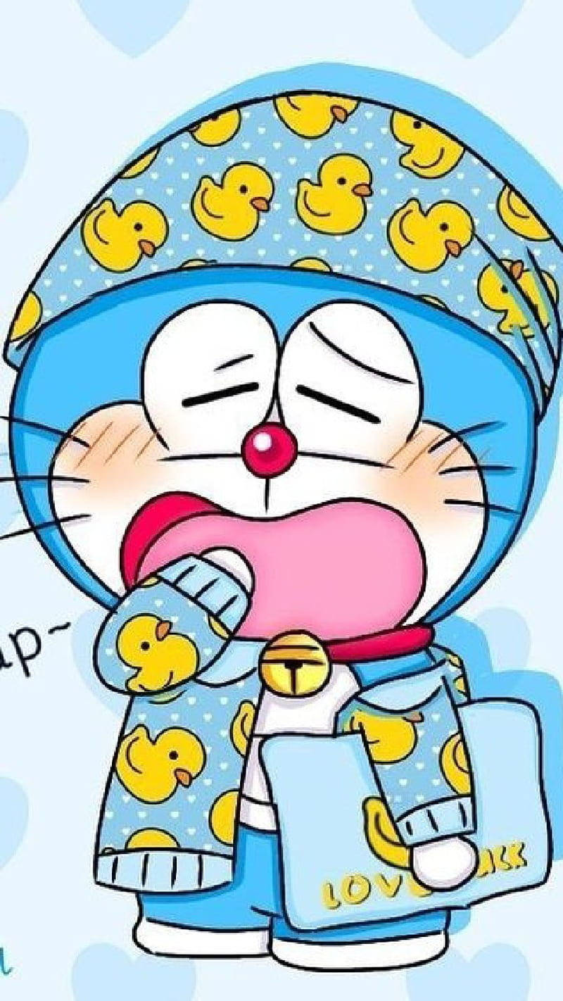 doraemon 4K 桌布 壁紙 — 穿著藍色鴨子圖案睡衣和帽子的哆啦A夢，在柔和的藍色背景前打呵欠，帶著睡意朦朧的表情。