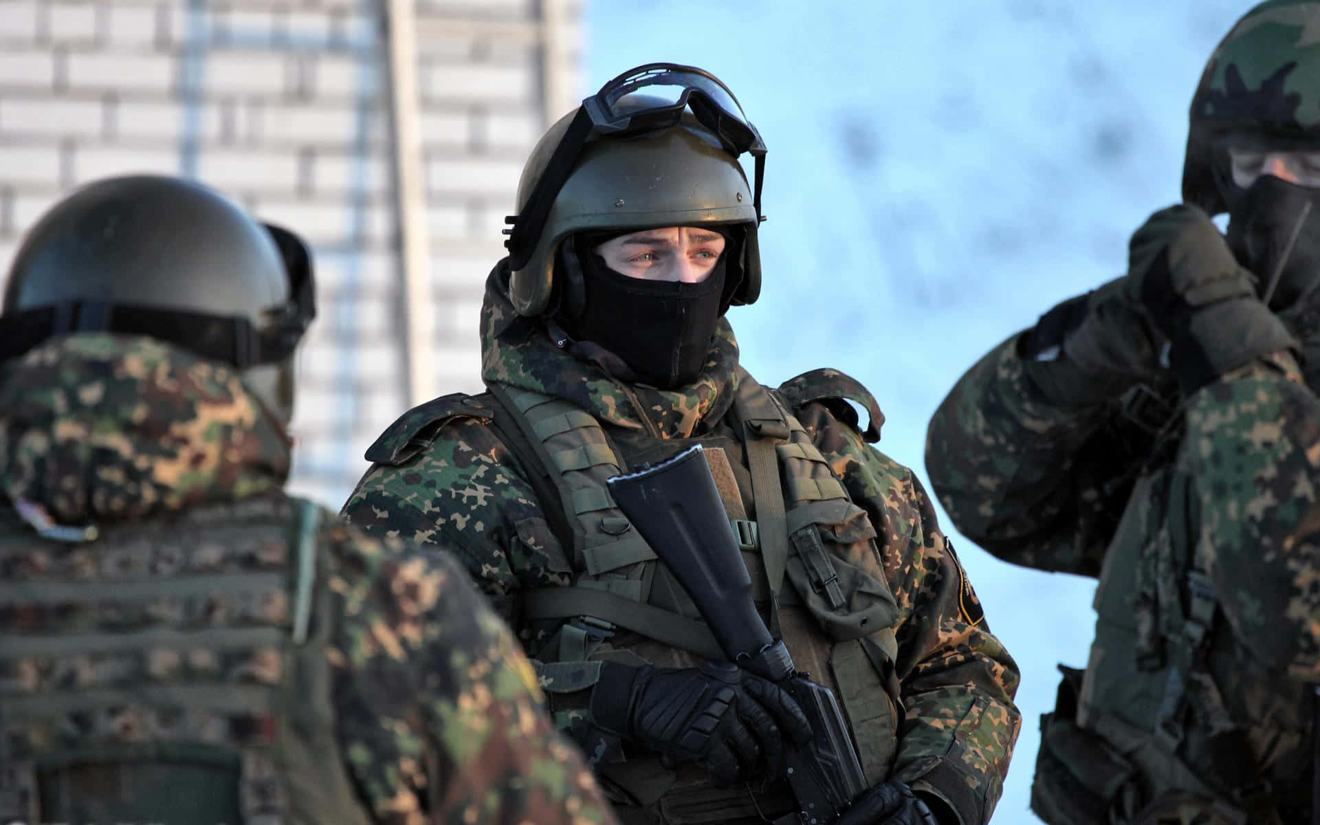 Special Forces 桌布 壁紙 — 穿著迷彩裝備和頭盔的士兵在戶外警覺地站立，背景可見積雪。