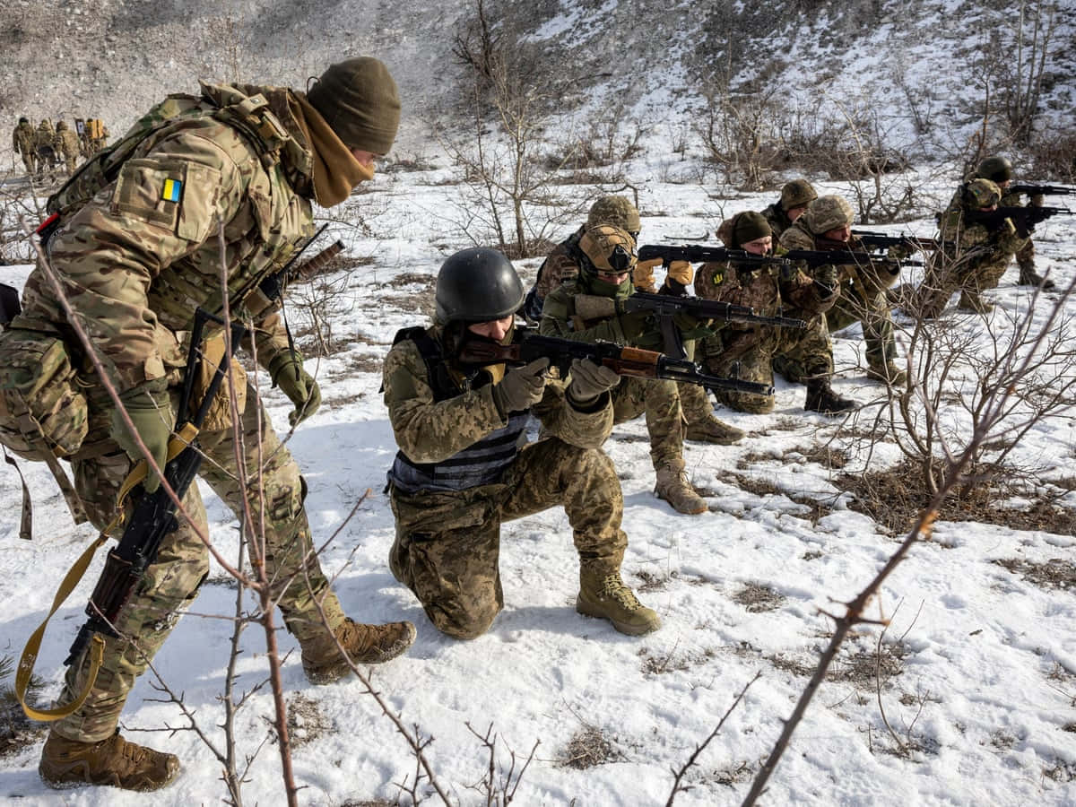 戰爭動圖 桌布 壁紙 — 穿著迷彩裝備的士兵在明亮的日光下，步槍指向前方，穿越雪地地形前進。