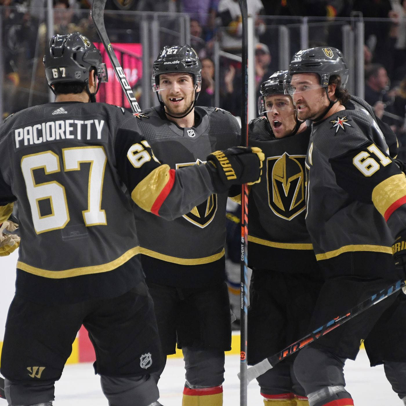 曲棍球 桌布 壁紙 — 穿著黑色和金色球衣的冰球運動員在冰上慶祝進球，表情激烈，球棍高舉。