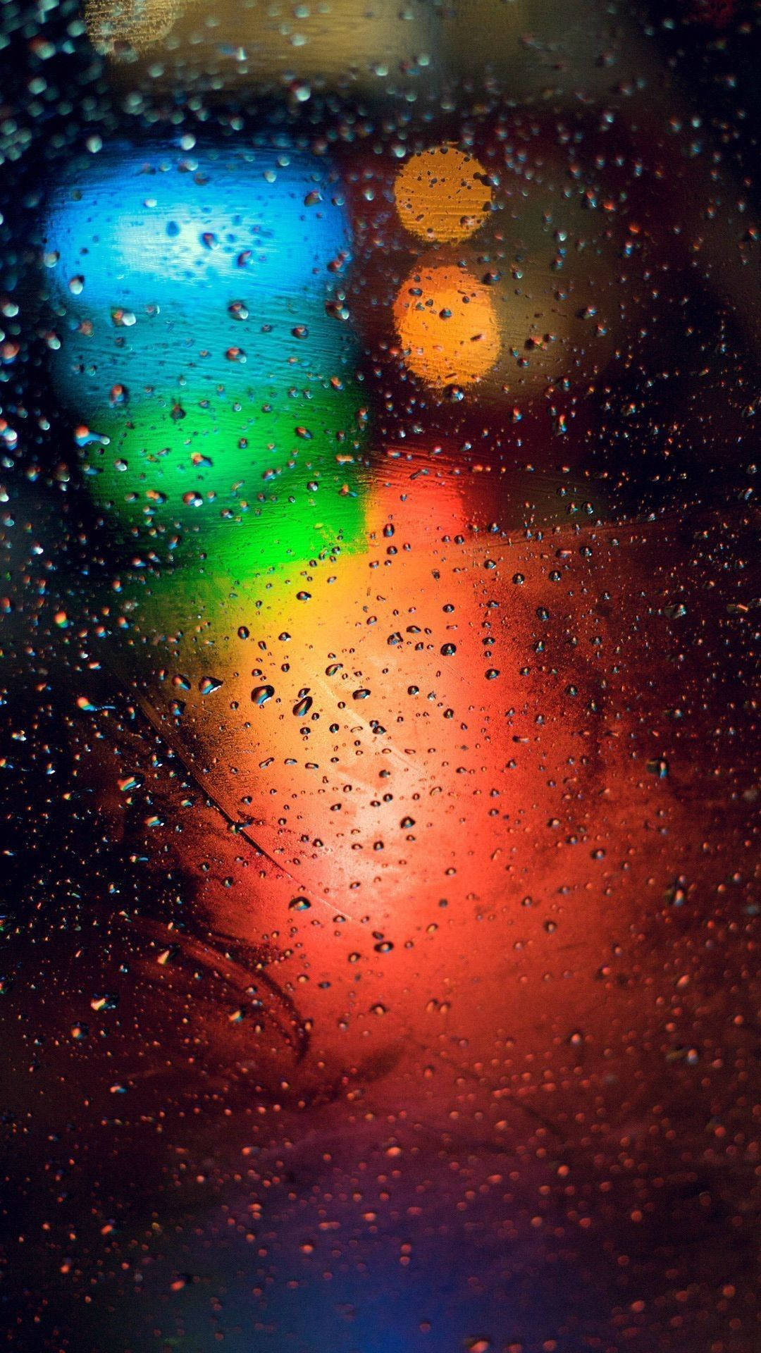 人像動態 桌布 壁紙 — 窗上的雨滴將充滿活力的城市燈光扭曲成色彩繽紛的散景條紋，映襯著黑暗的夜晚背景。
