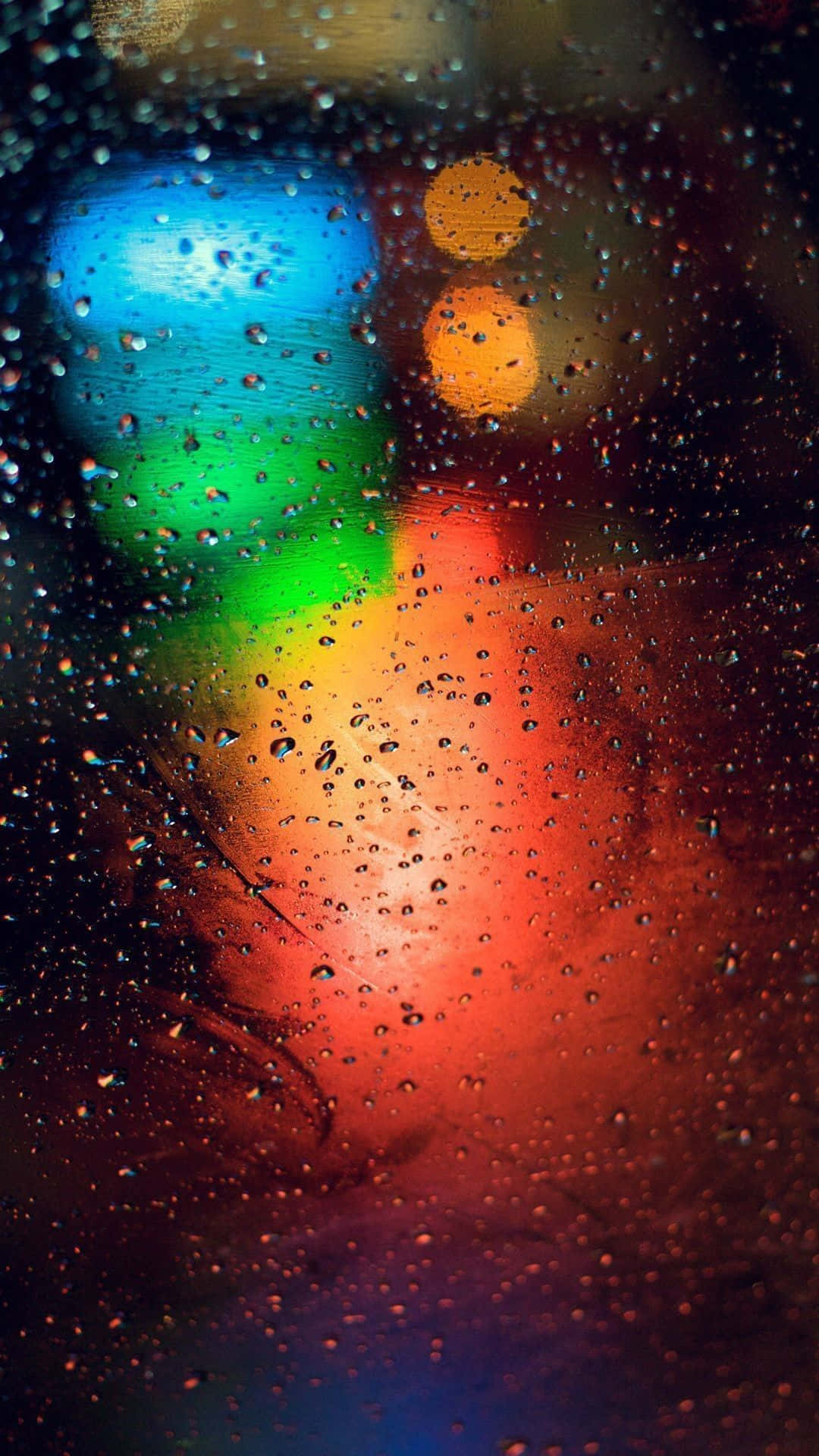 Bokeh 桌布 壁紙 — 窗上的雨滴將充滿活力的城市燈光扭曲成色彩繽紛的散景條紋，映襯著黑暗的夜晚背景。