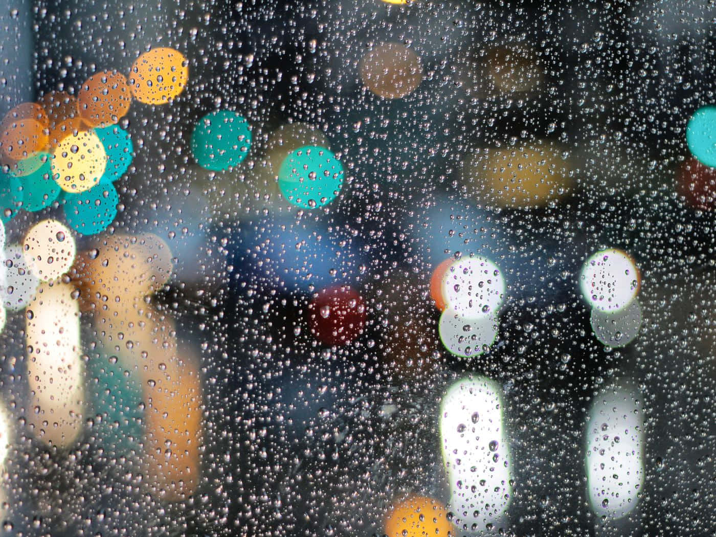 Rainy 桌布 壁紙 — 窗上的雨滴將色彩繽紛的城市燈光扭曲成柔和發光的圓圈，映襯在黑暗的背景上。
