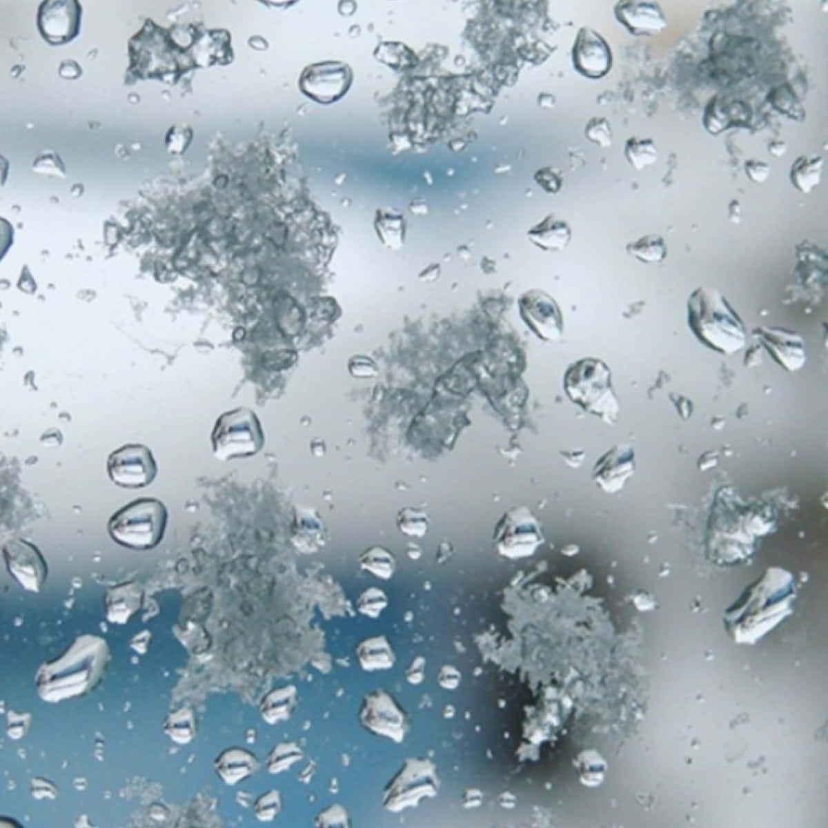 窗上的雨滴和霜，背景為模糊的天空。 — 雪花 GIF 壁紙