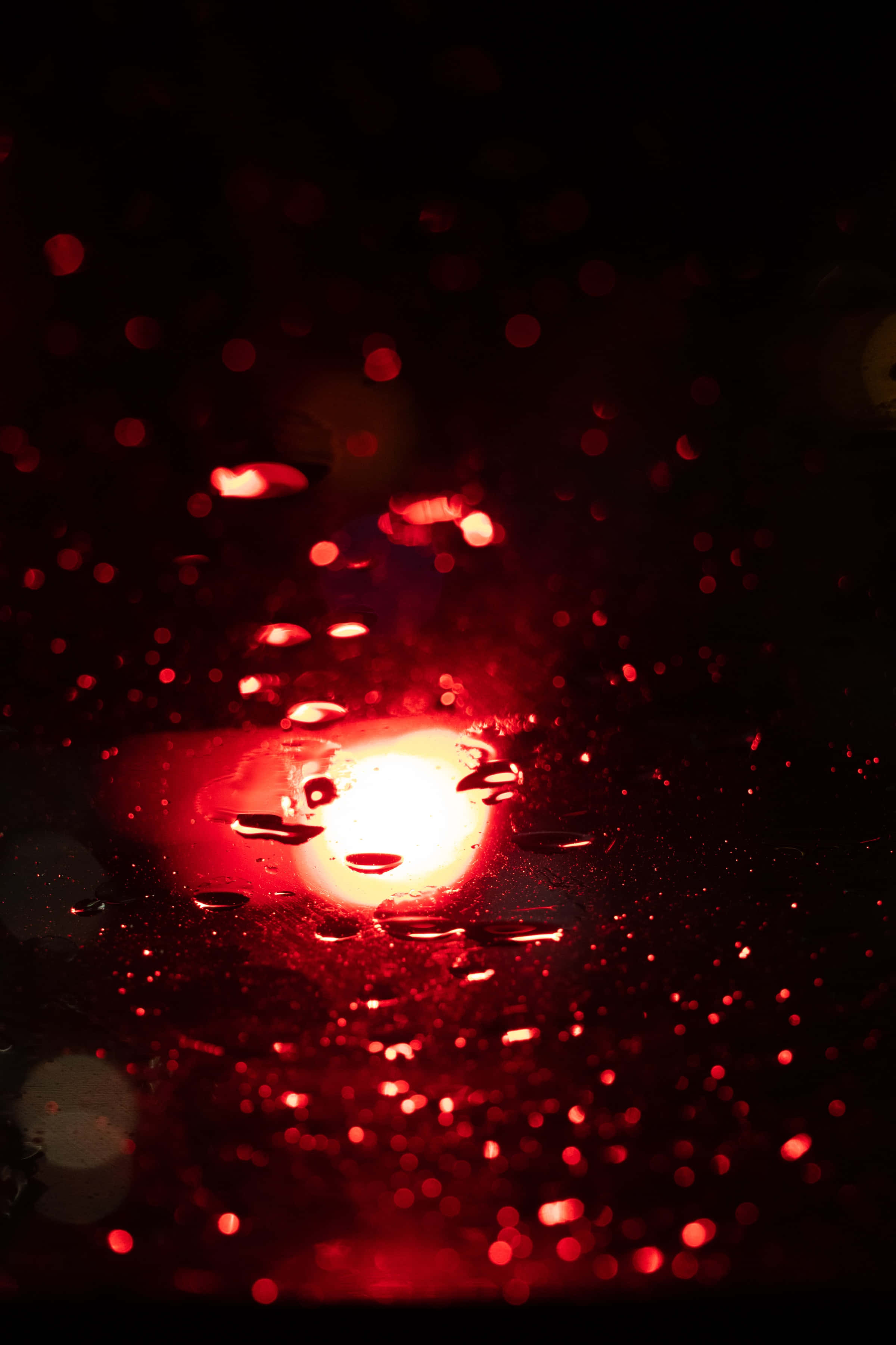 Red Glitter 桌布 壁紙 — 窗上雨滴的特寫，在漆黑的夜晚背景下反射出微弱的紅光。