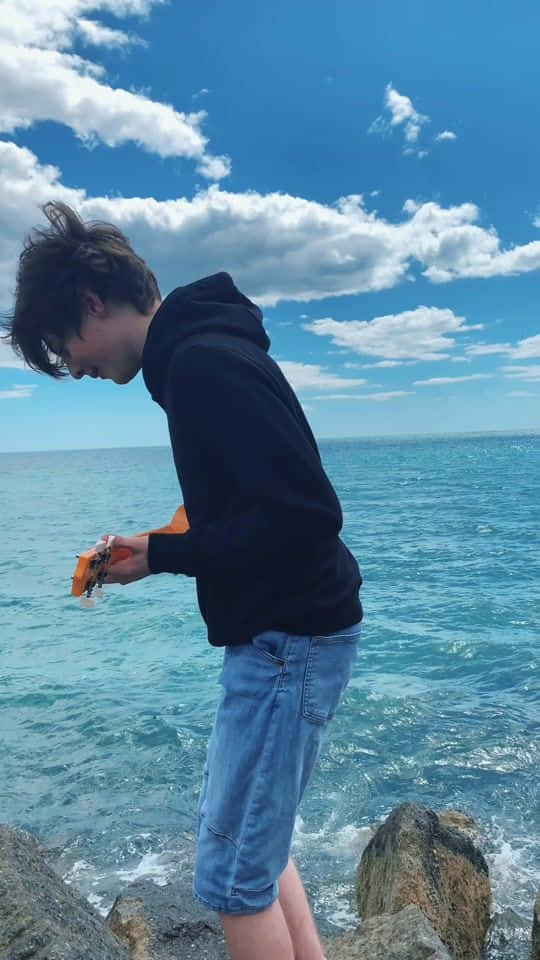 站在海邊岩石上的年輕男子 壁紙