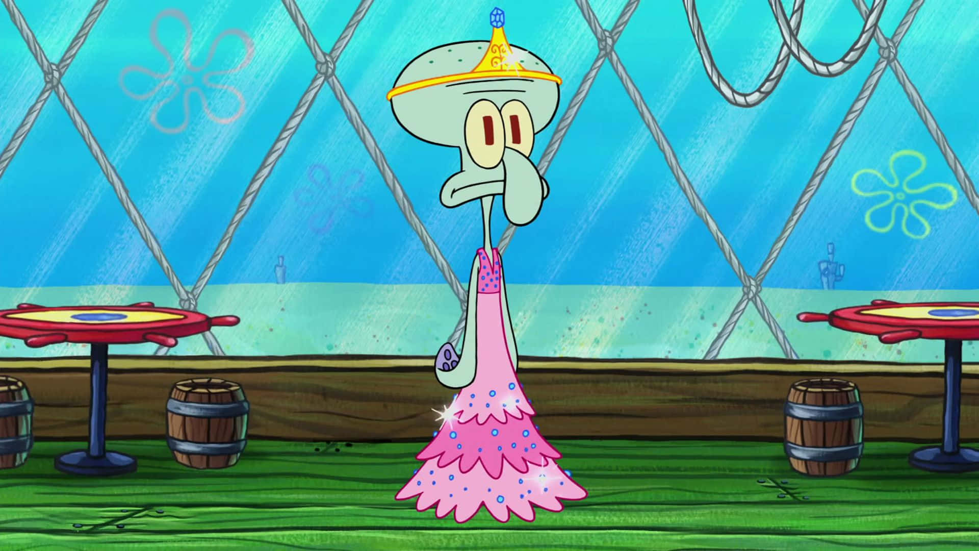 Aesthetic Squidward 桌布 壁紙 — 章魚哥穿著粉紅色閃亮長袍和皇冠，站在光線昏暗的水下餐廳，內有繩網和桶桌。