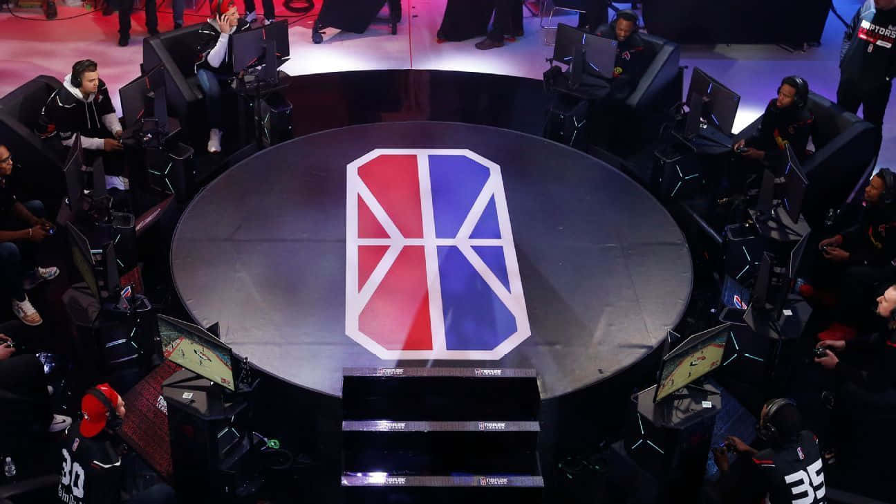 Esports 桌布 壁紙 — 競技電競選手在中央舞台周圍的站點上高度專注，舞台上有醒目的紅藍標誌。