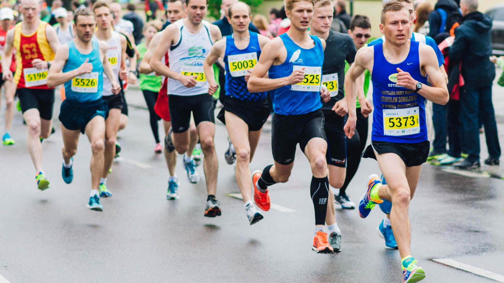 Best Sports 桌布 壁紙 — 競賽中的男性跑者穿著運動裝備，在潮濕的城市街道上衝刺。