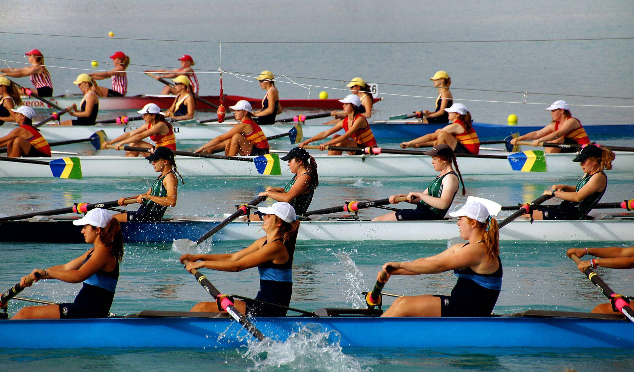 Teamwork 桌布 壁紙 — 競賽划艇選手以同步動作在平靜水面上划過色彩繽紛的賽艇。