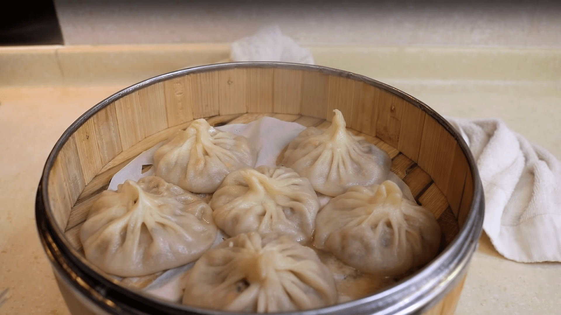 steam 桌布 壁紙 — 竹蒸籠裡冒著蒸氣的餃子，旁邊放著一條柔軟毛巾在檯面上。