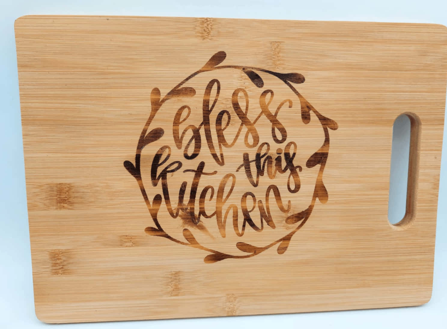Wood Burning 桌布 壁紙 — 竹製砧板，上面有葉子花環設計，內有草書刻字 'bless this kitchen'。