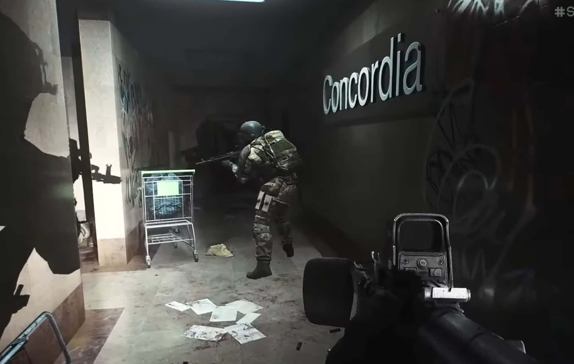 Fps Games 桌布 壁紙 — 第一人稱射擊視角，一名士兵在光線昏暗、佈滿塗鴉的地下走廊前進，地上散落紙張和一部購物車。