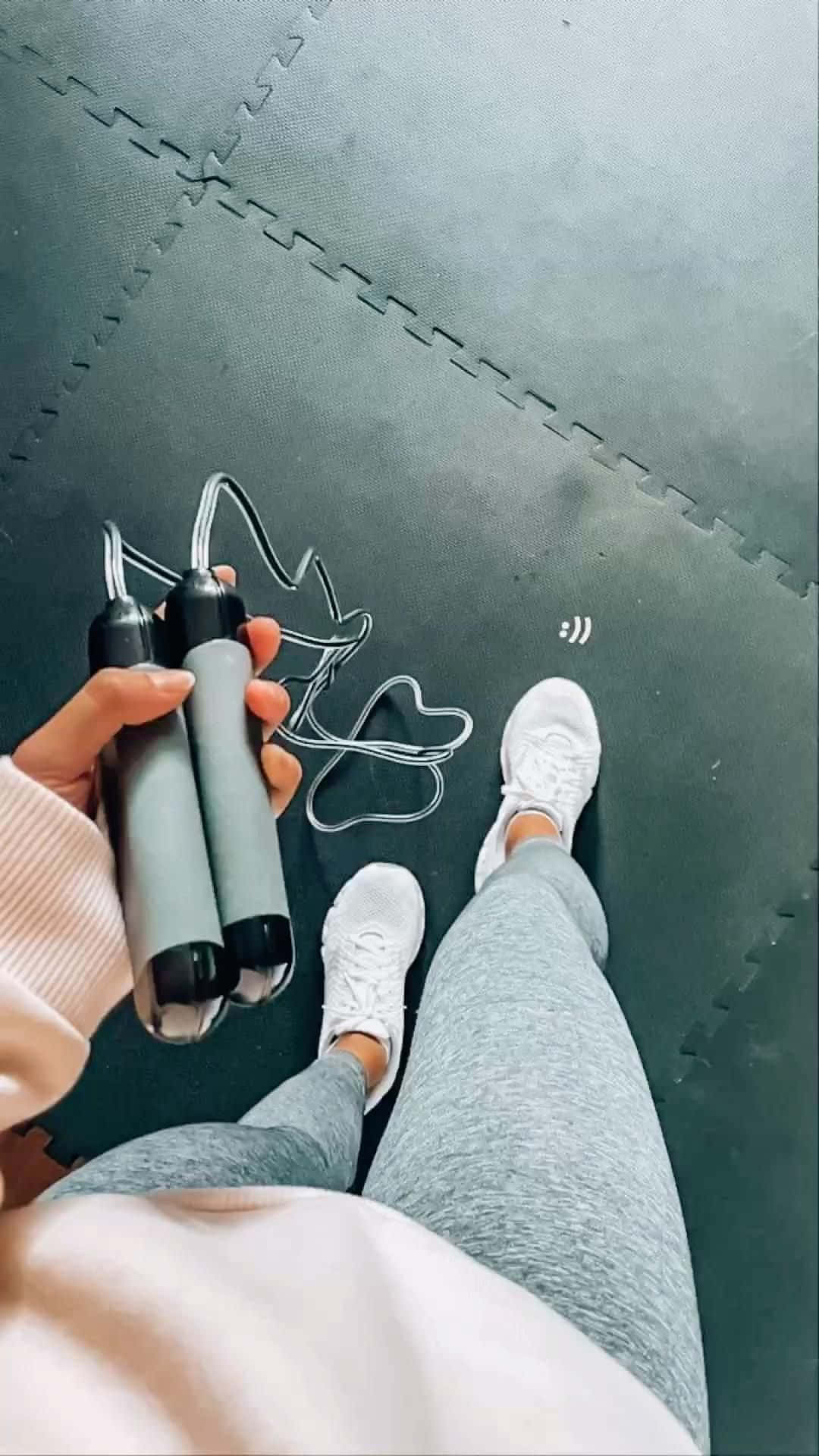 Training 桌布 壁紙 — 第一人稱視角，一個人手持跳繩，站在深灰色互鎖式泡棉墊上，準備鍛鍊。