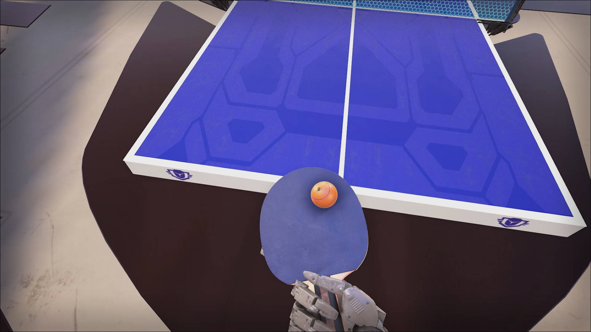 Table Tennis 桌布 壁紙 — 第一人稱視角，一隻機械手拿著一個帶有橙色球的球拍，位於帶有幾何圖案的藍色乒乓球桌上方。