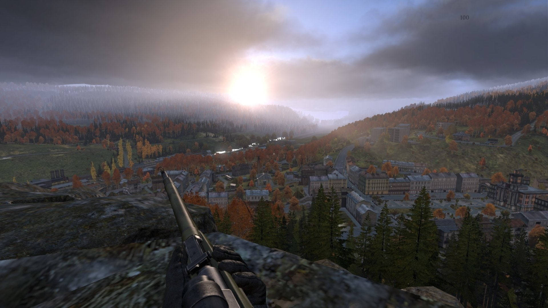 Dayz Desktop 桌布 壁紙 — 第一人稱視角，俯瞰日出時分坐落在森林山丘中的霧氣瀰漫的秋日小鎮，手中握著步槍。