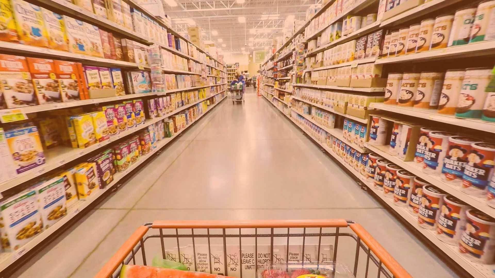 Shopping 桌布 壁紙 — 第一人稱視角推著購物車沿著燈光明亮的雜貨通道，通道上擺滿了穀物和罐頭食品。