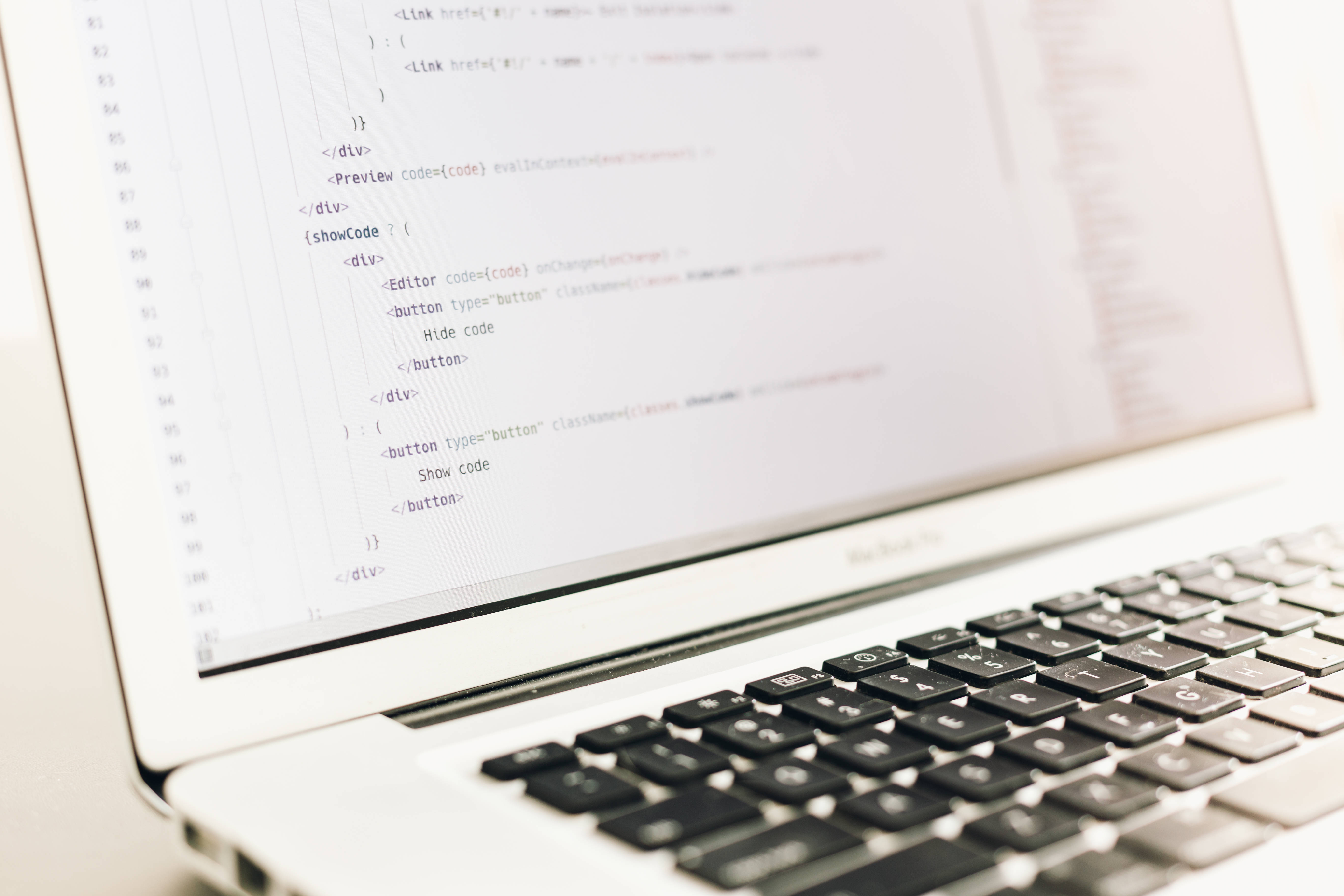 MacBook 動態圖片 桌布 壁紙 — 筆記型電腦特寫，顯示HTML和JavaScript程式碼行，前景有模糊鍵盤。