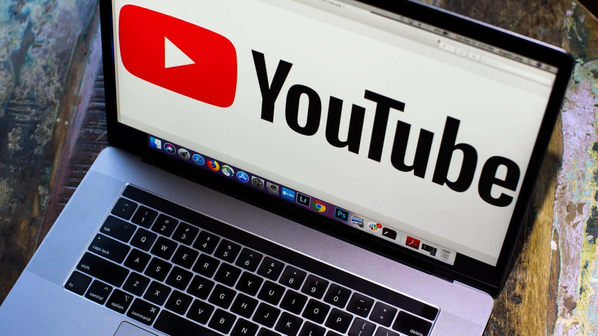 YouTube 桌布 壁紙 — 筆記型電腦螢幕上顯示 YouTube 標誌，背景為木桌。