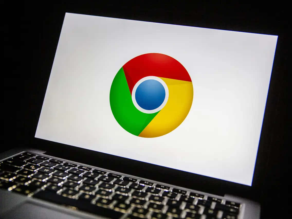 Chrome 桌布 壁紙 — 筆記型電腦螢幕在深色背景上顯示色彩繽紛的Google Chrome標誌，並可見鍵盤。