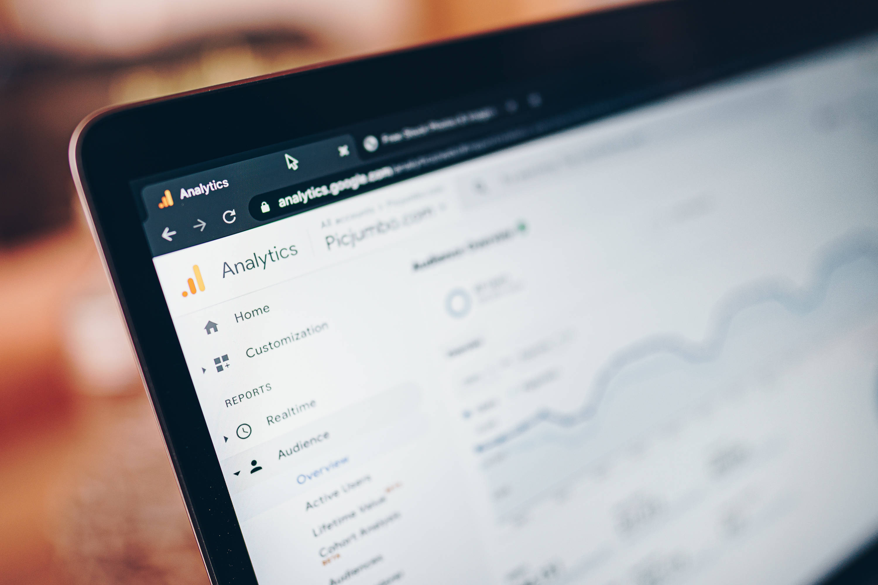 Website 桌布 壁紙 — 筆記型電腦螢幕特寫，顯示Google Analytics儀表板，背景模糊。