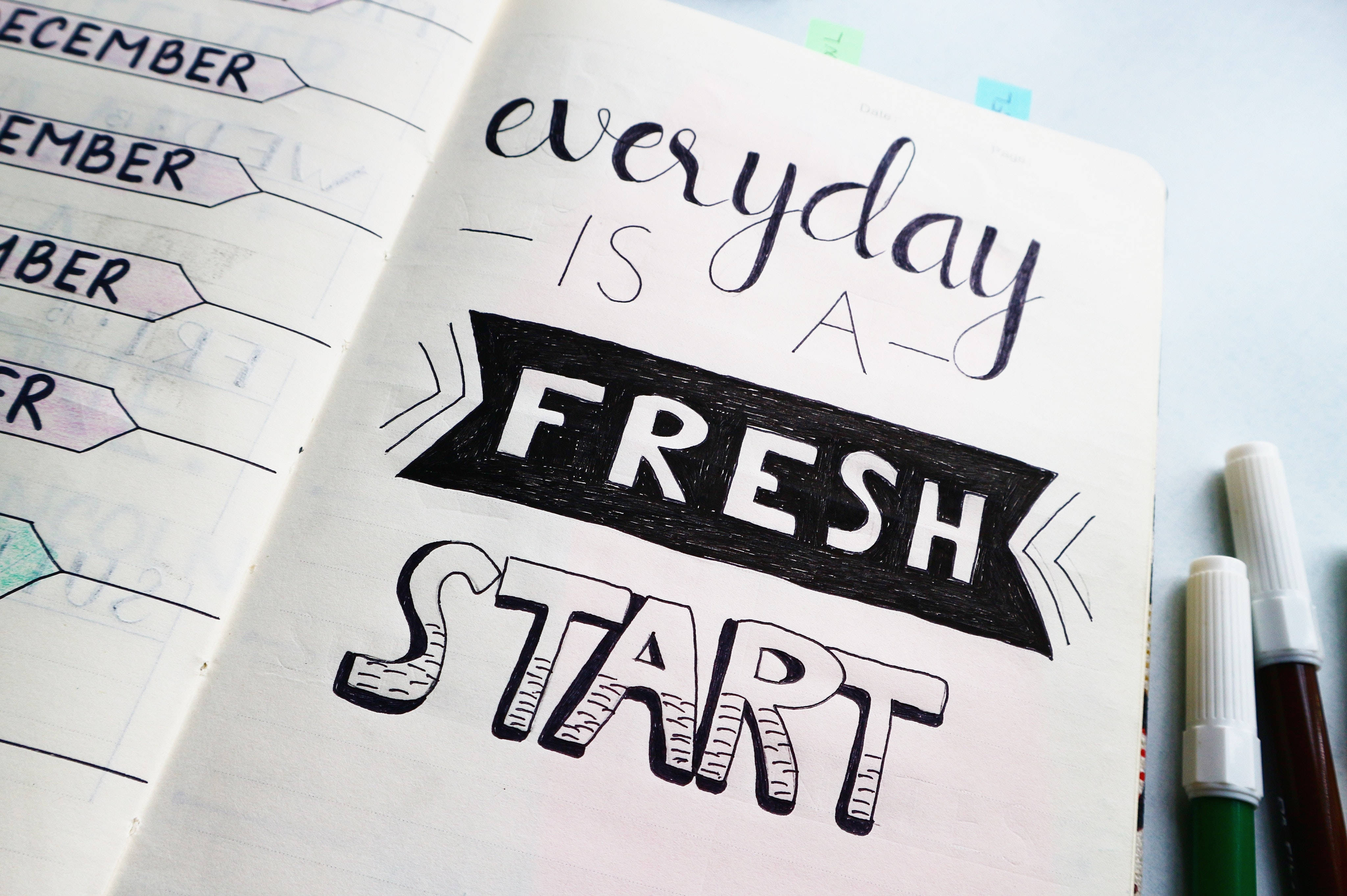 Inspirational Quotes 桌布 壁紙 — 筆記本頁面的特寫，上面用粗體黑色墨水寫著「每一天都是新的開始」，背景為日曆佈局。