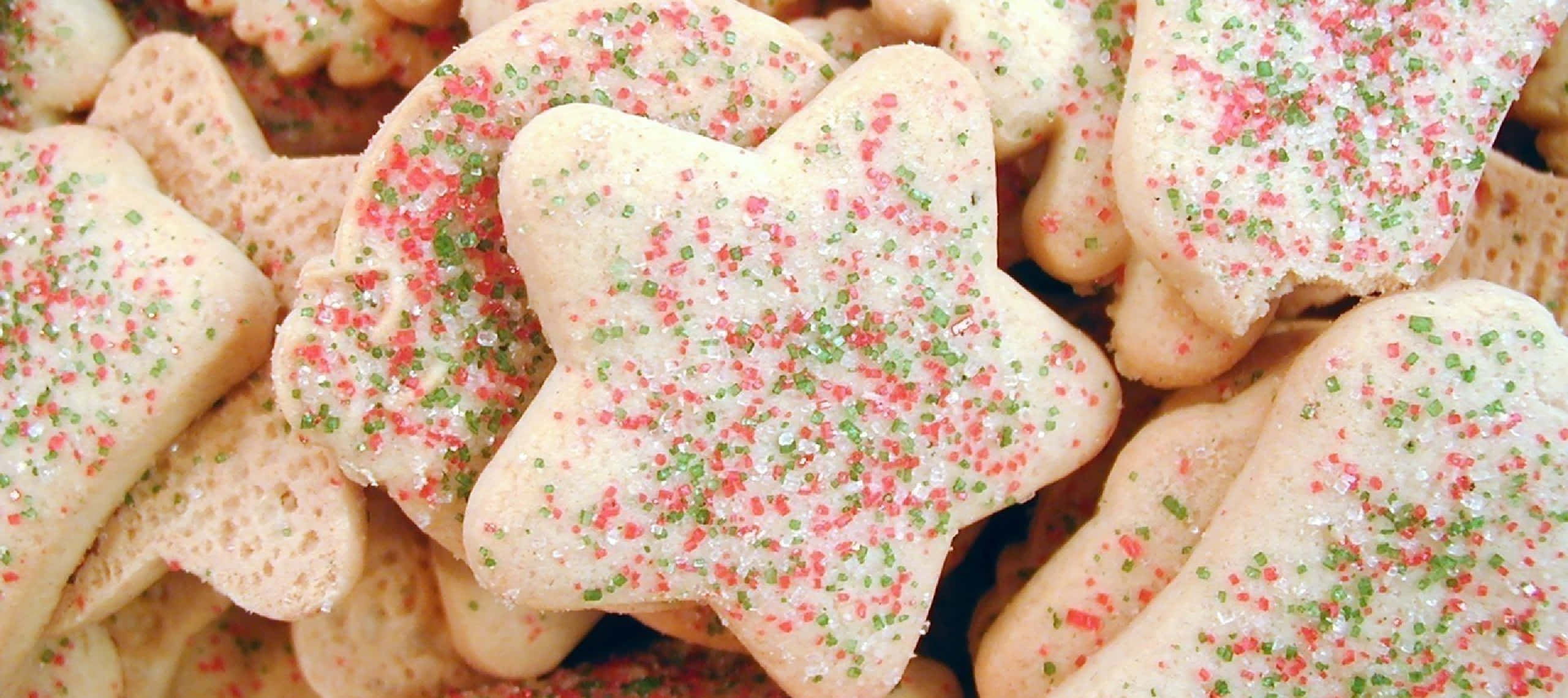 1440p Cookies 桌布 壁紙 — 節日星星和骨頭形狀餅乾的特寫，撒上紅色、綠色和白色糖粒。
