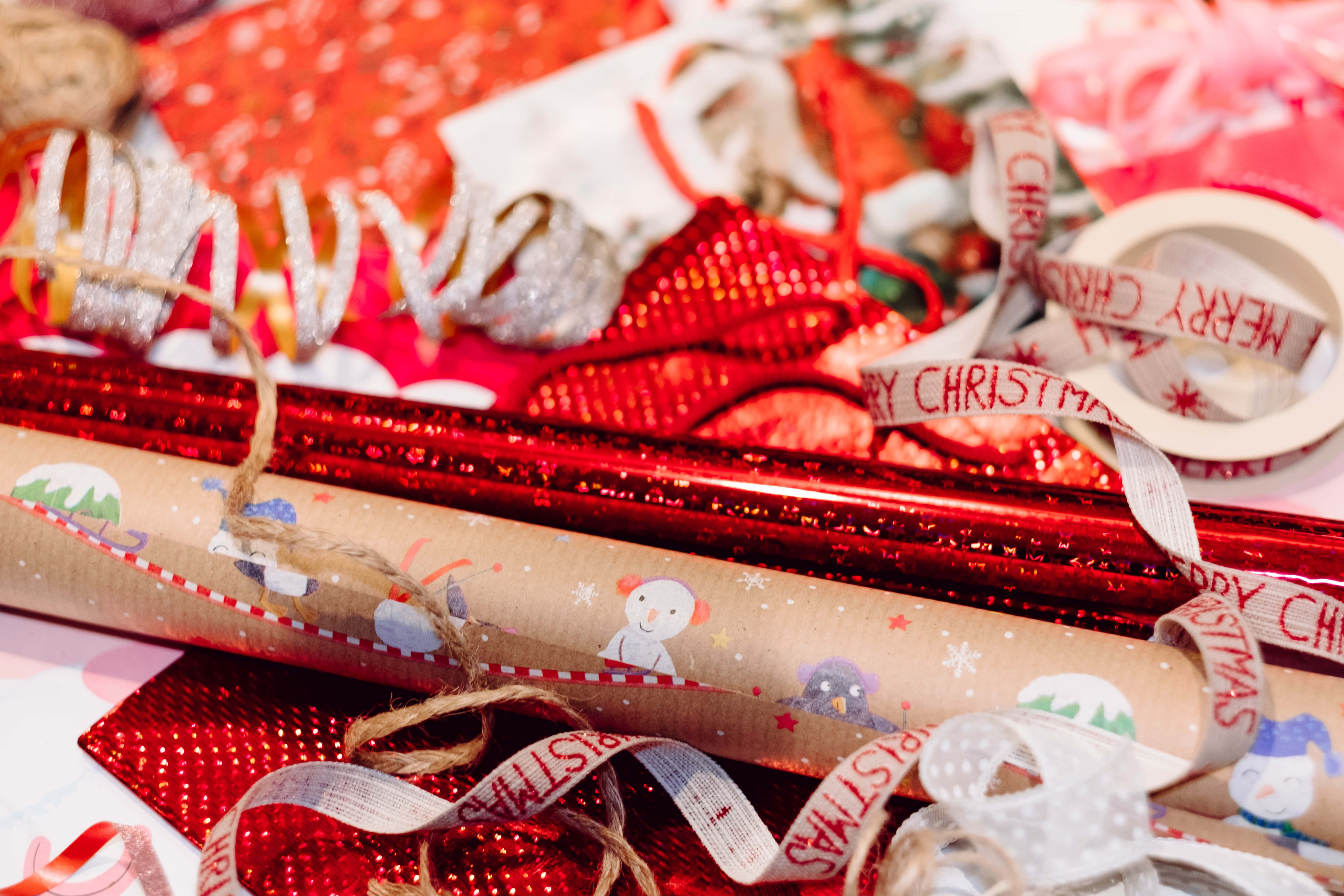 Christmas Scene 桌布 壁紙 — 節日特寫：聖誕包裝紙卷、絲帶和膠帶散落在鮮豔的紅色、白色和金色中。