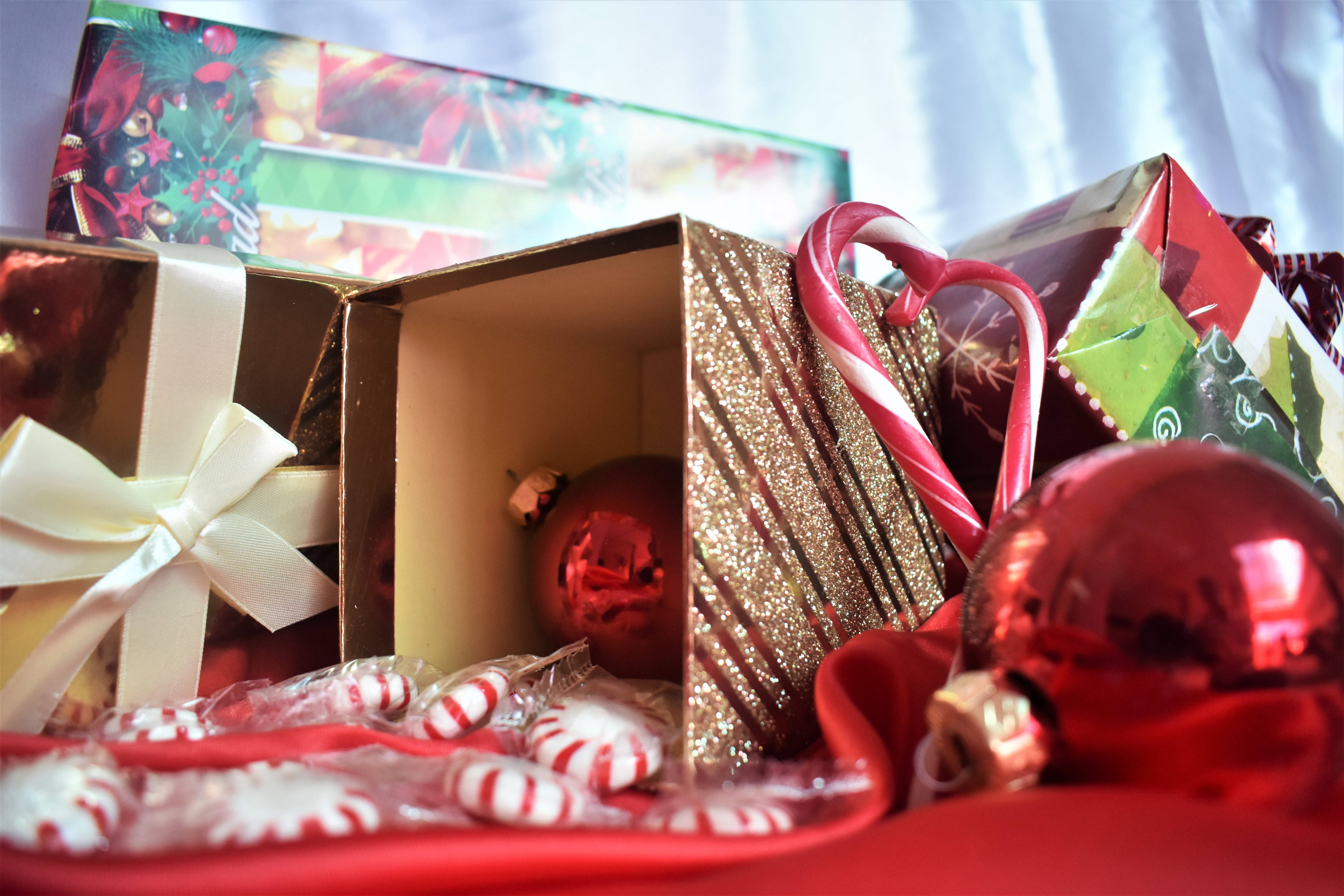 merry christmas elf 桌布 壁紙 — 節日特寫：聖誕禮物、拐杖糖和紅色裝飾品排列在紅色布料上，背景燈光柔和。
