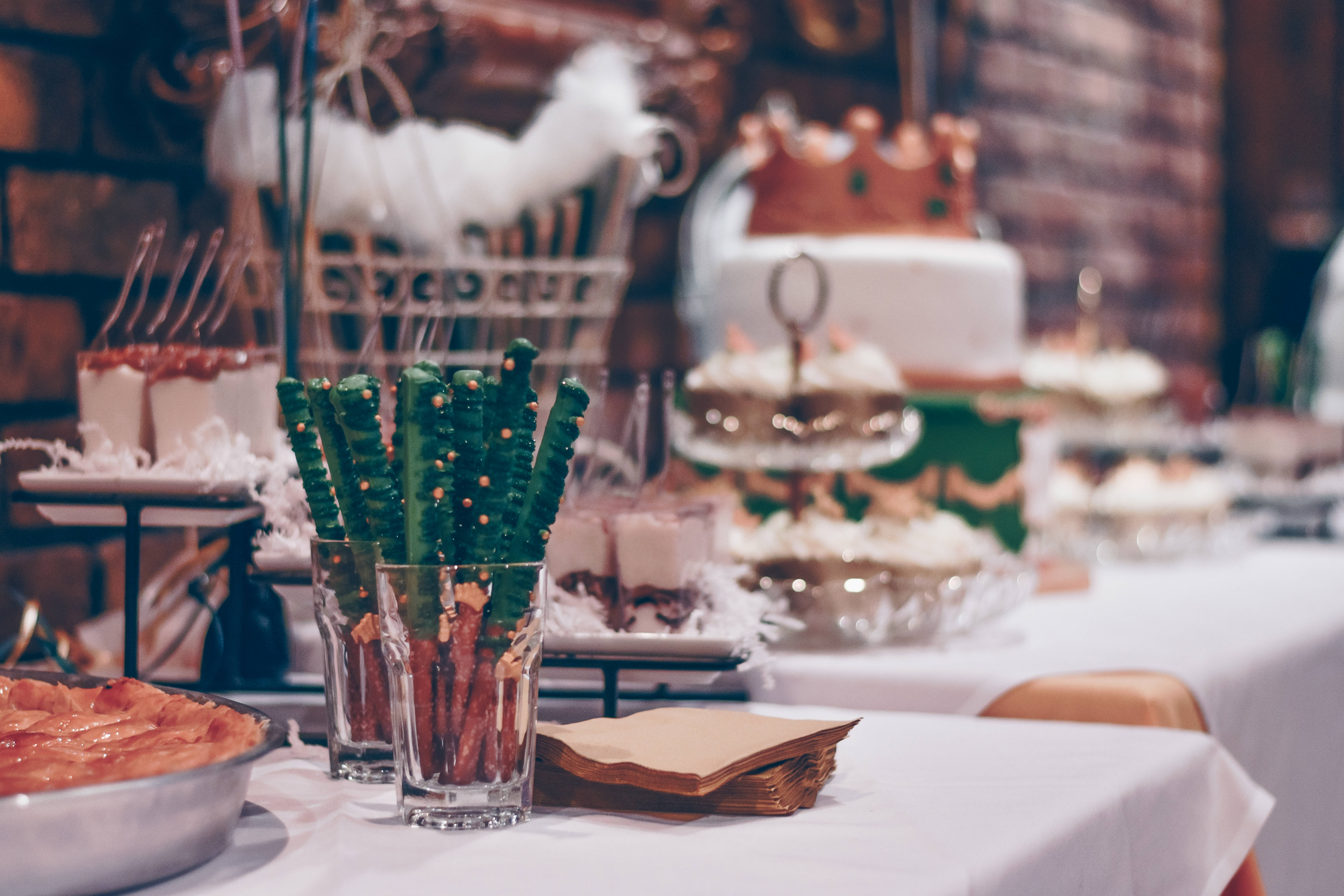 Bachelorette 桌布 壁紙 — 節日甜品桌，上面有白色蛋糕、巧克力脆餅和各式糖果，在溫暖的環境燈光下。