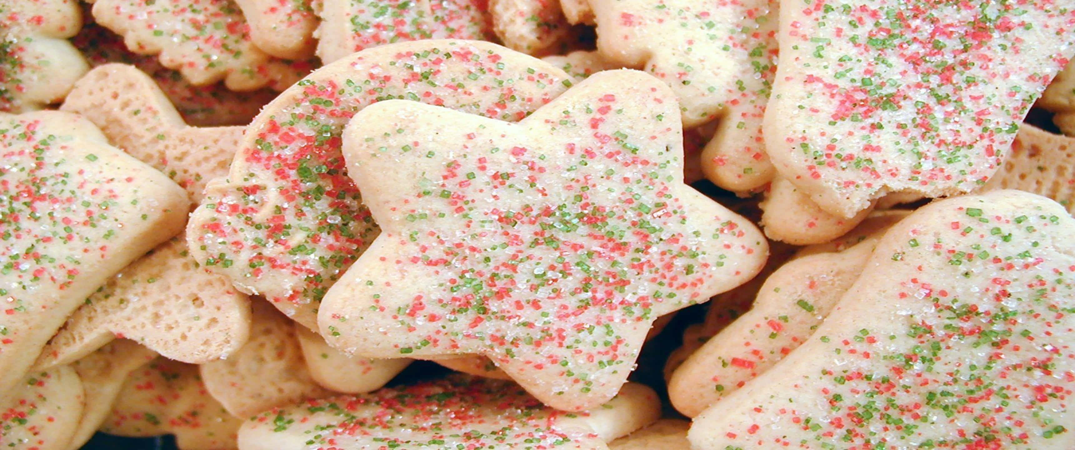 Cookies 桌布 壁紙 — 節日糖餅乾的特寫，形狀為星星和樹木，撒上紅色和綠色的糖粒。