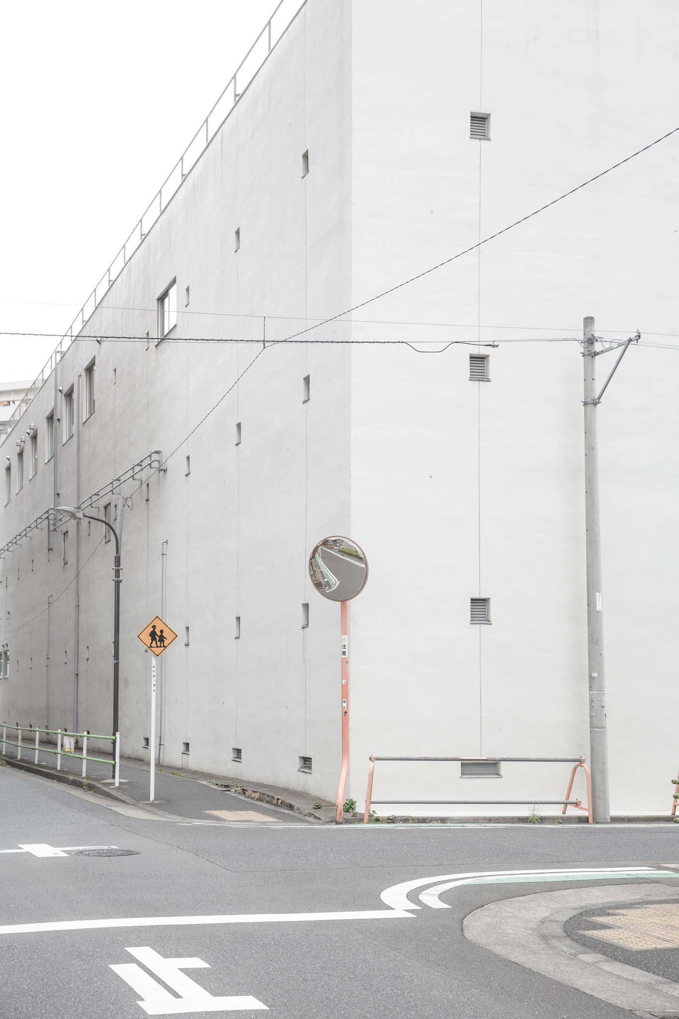 灰色美學動圖 桌布 壁紙 — 簡約城市街角，有一座大型白色建築、交通鏡和行人穿越道標誌，天空多雲。