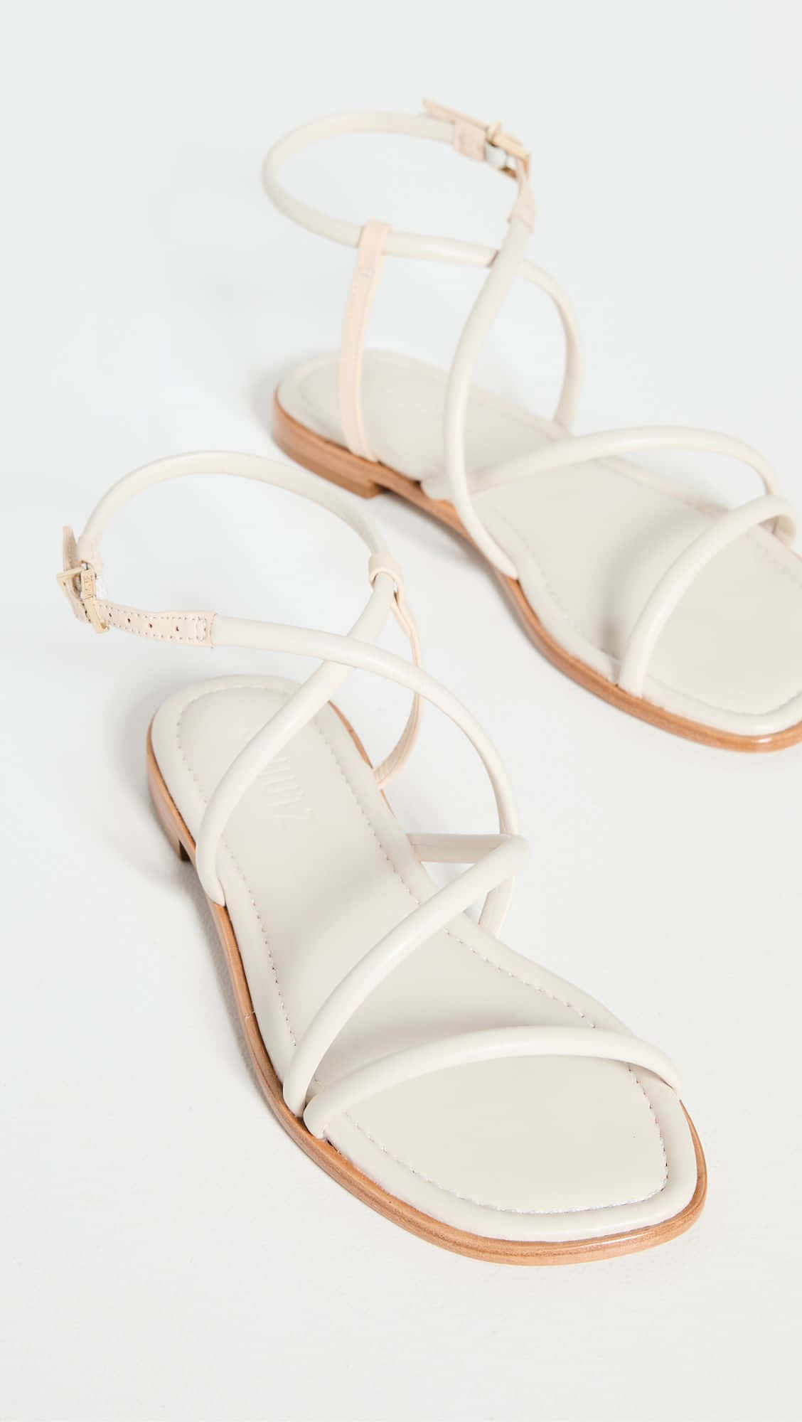 Sandals 桌布 壁紙 — 簡約奶油色綁帶涼鞋，淺棕色鞋底，在乾淨的白色背景上拍攝。