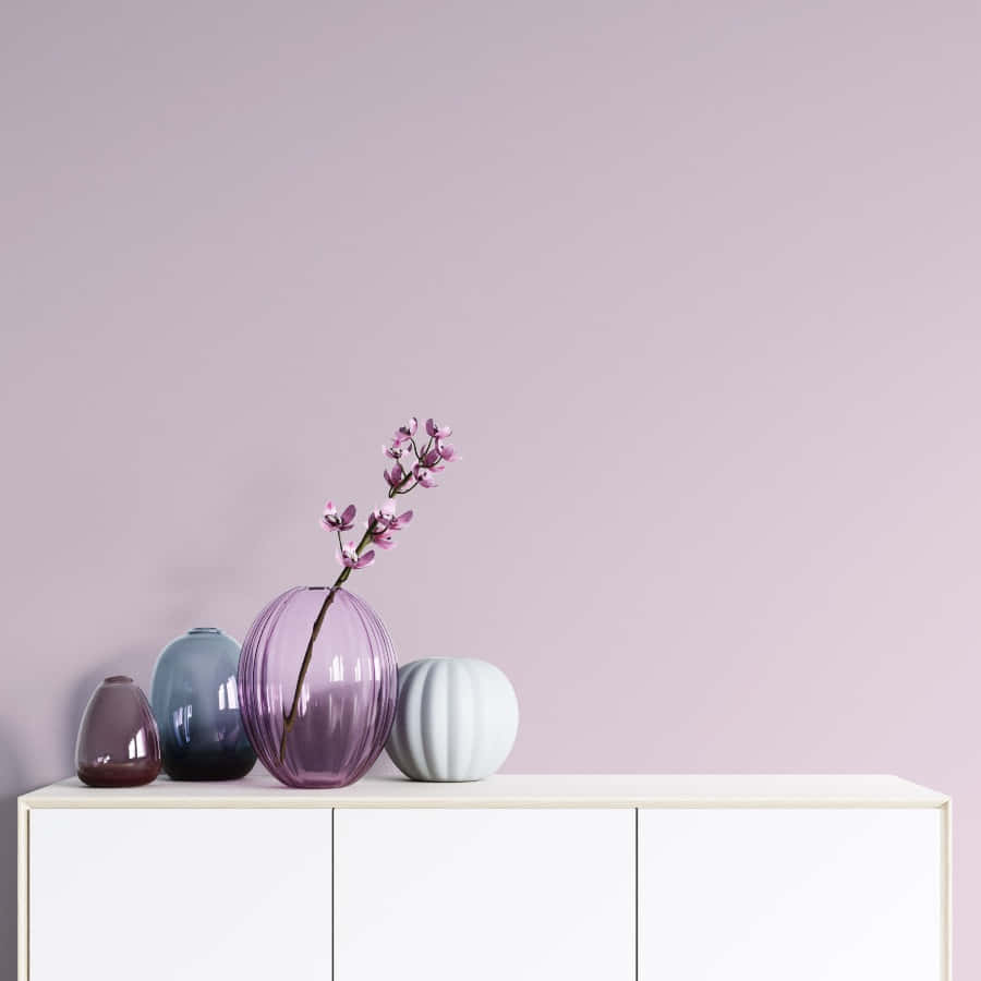 Lilac Color 桌布 壁紙 — 簡約室內場景，粉紅色牆壁和白色櫃子，擺放著色彩繽紛的花瓶和精緻的粉紅色花枝。