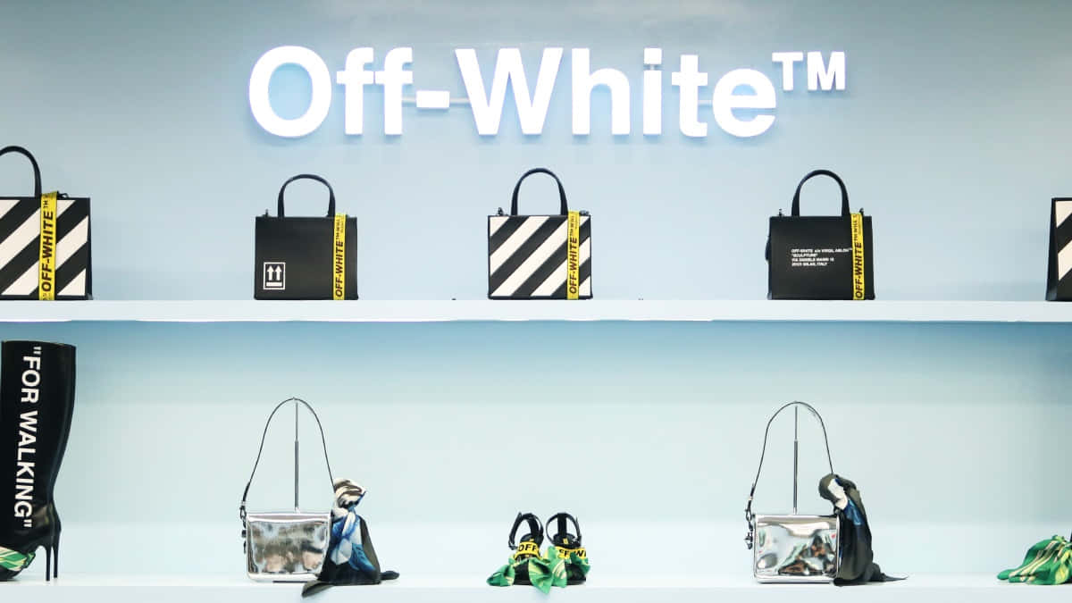 off white 桌布 壁紙 — 簡約展示Off-White品牌手提袋和靴子，排列在白色層架上，背景為淺藍色牆壁，品牌名稱以粗體白色字母呈現。