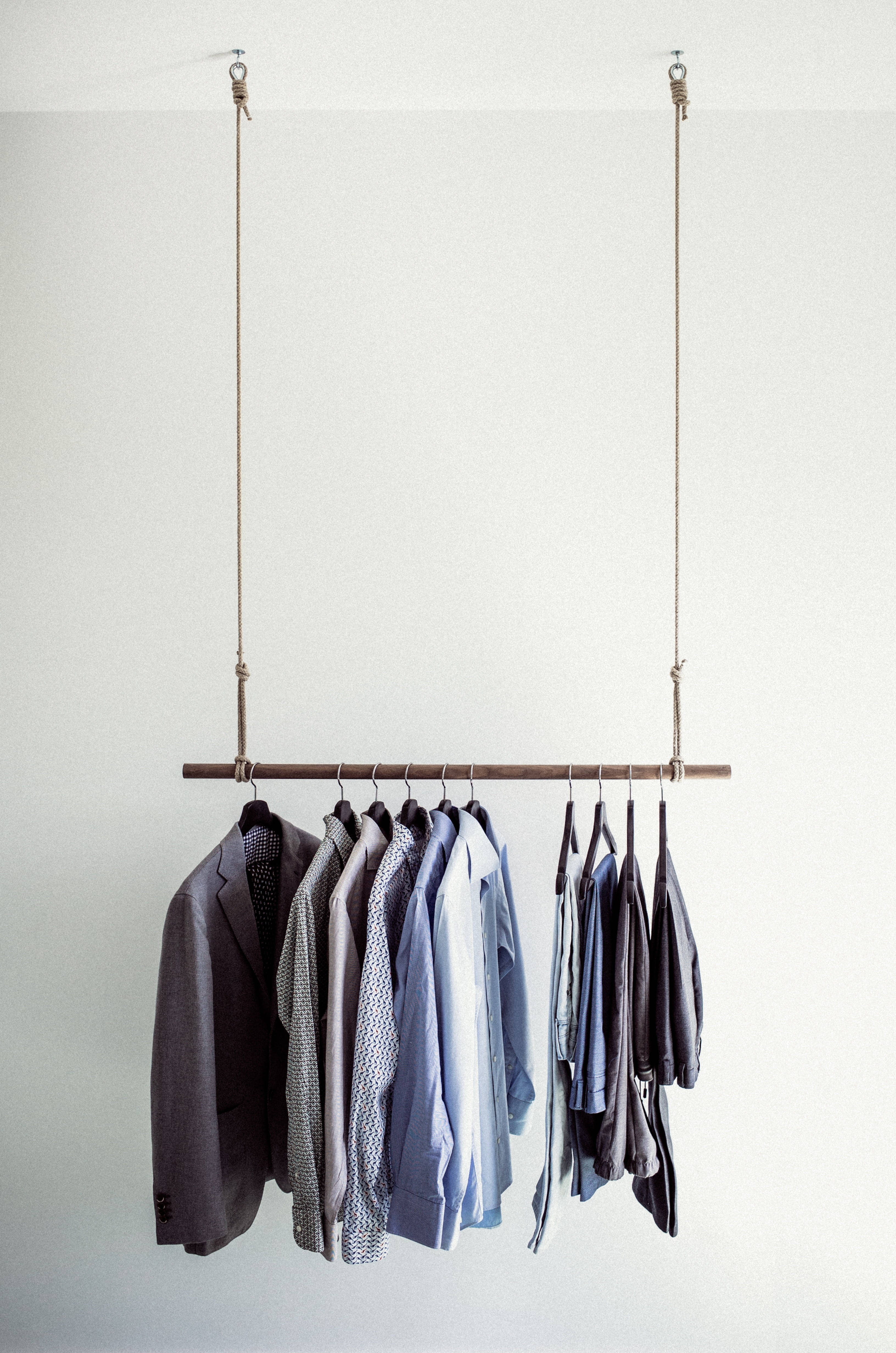Clothes 桌布 壁紙 — 簡約掛衣架，整齊排列的襯衫和西裝外套，背景為純白牆壁。
