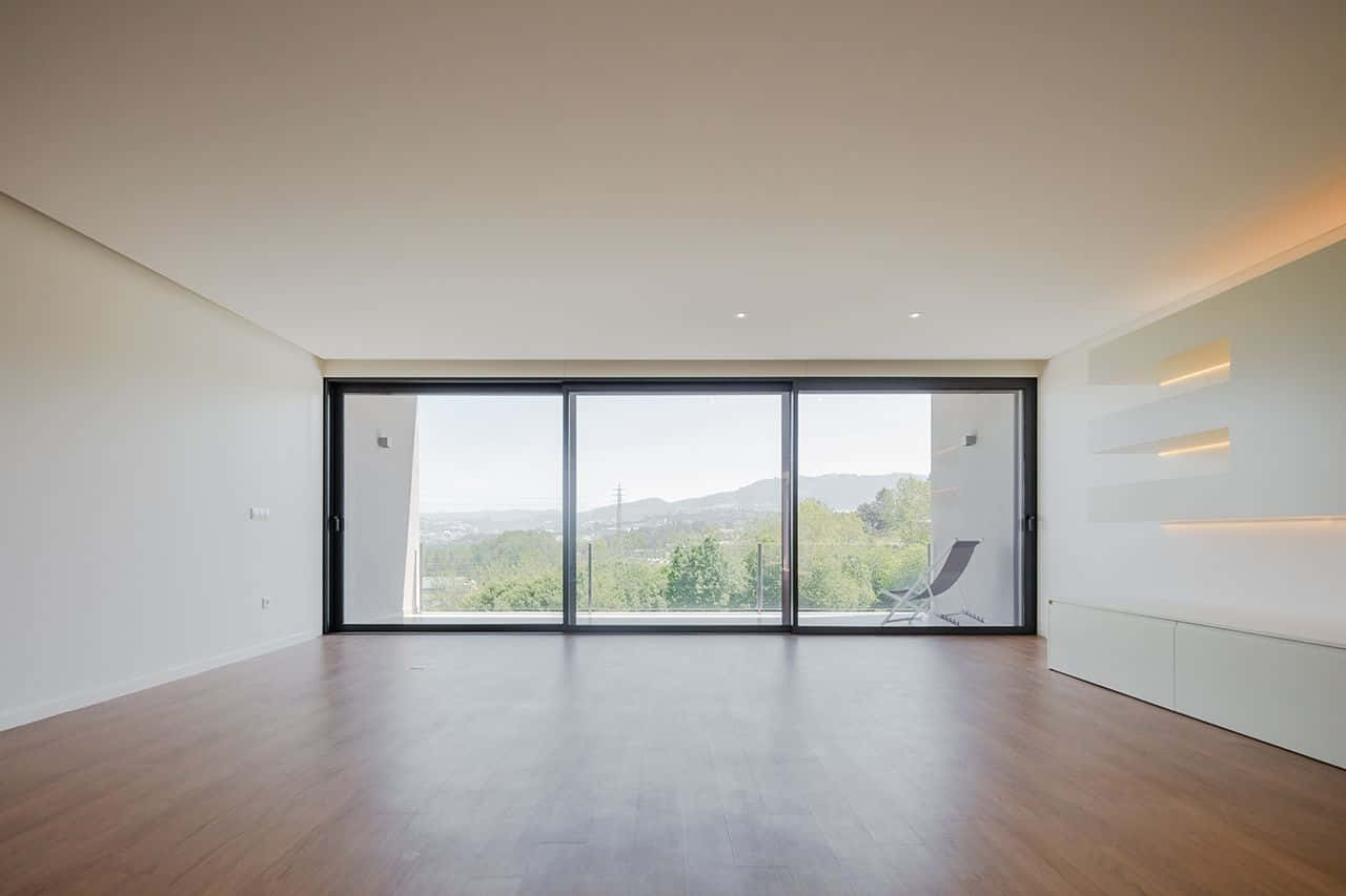 Empty Room 桌布 壁紙 — 簡約現代房間，木地板和大型玻璃門框出鬱鬱蔥蔥的山坡景色。