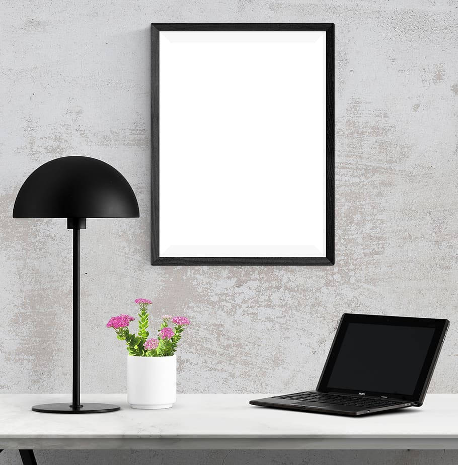 Frame 桌布 壁紙 — 簡約現代書桌佈置，配有黑色檯燈、手提電腦和粉紅色花朵，背景為紋理灰色牆壁。
