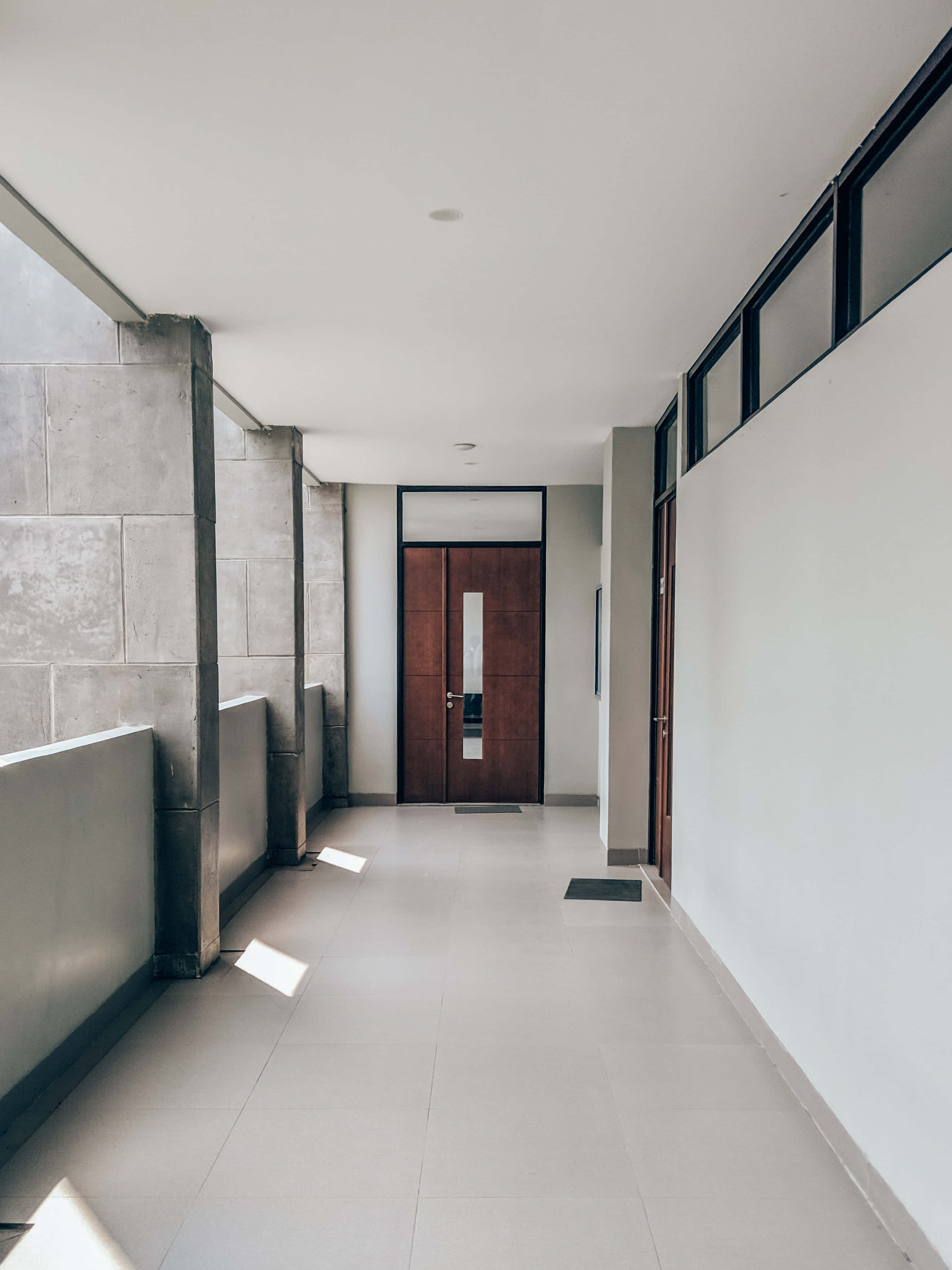 hallway 桌布 壁紙 — 簡約現代走廊，混凝土牆壁和白色瓷磚地板通向木門。