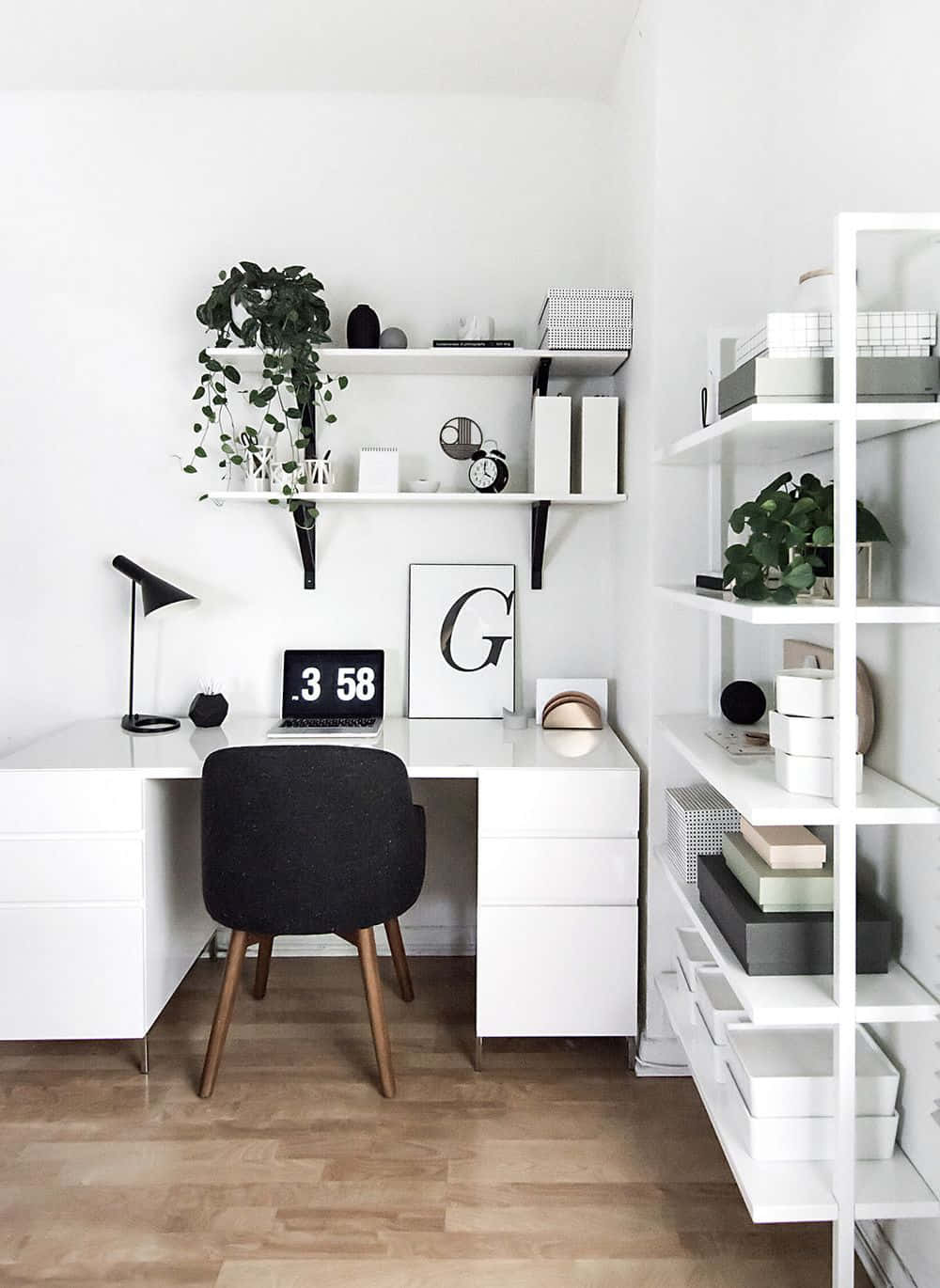 Minimalist Design 桌布 壁紙 — 簡約白色居家辦公室，配備時尚書桌、黑色椅子、木地板，以及放置植物、書籍和裝飾品的浮動層架。