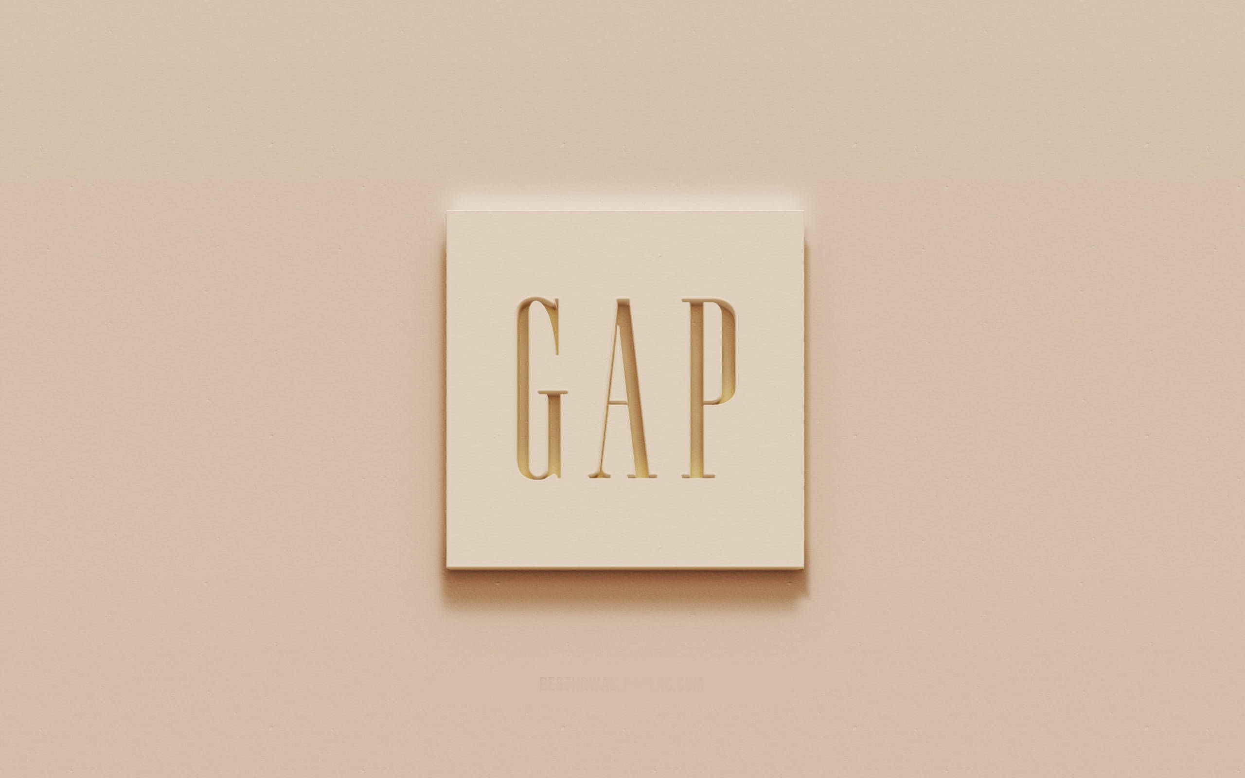 Gap 桌布 壁紙 — 簡約米色牆上有一個方形奶油色牌匾，帶有金色壓花GAP標誌，投射出柔和陰影。