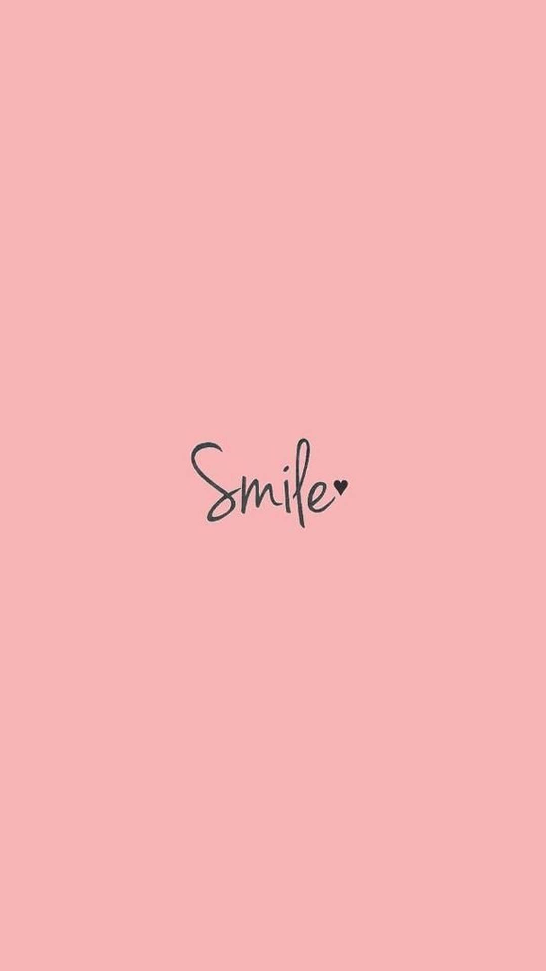 粉紅色背景，黑色草書寫著「Smile」，i 上方的點被心形取代。 — 美學字眼 壁紙