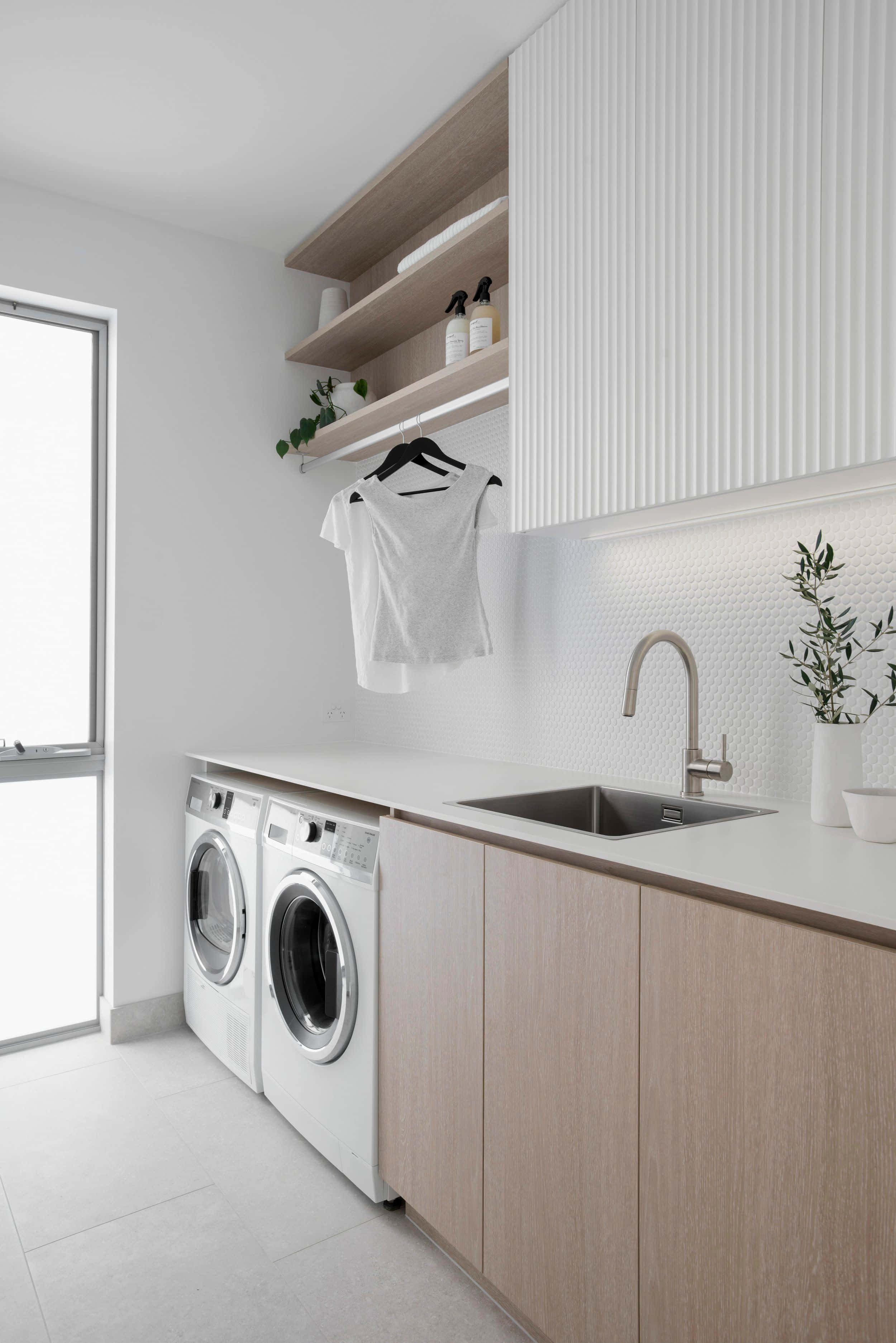 Laundry Room 桌布 壁紙 — 簡約風洗衣房，配有淺色木櫃、白色電器，以及掛在窗邊的白色襯衫。