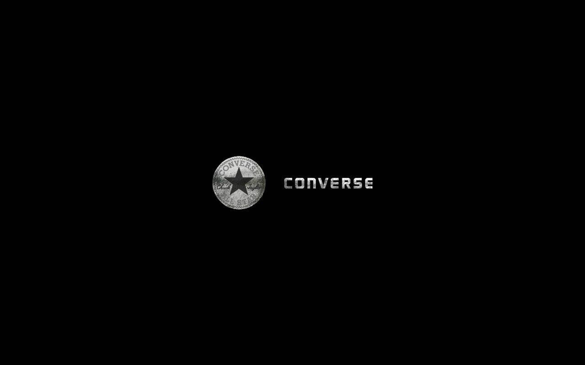 Converse Logo 桌布 壁紙 — 簡約黑色背景上，經典的Converse標誌以金屬銀色呈現，包含星形徽章和品牌名稱。