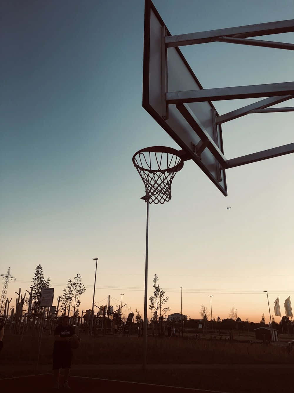 Basketball Aesthetic 桌布 壁紙 — 籃球框的剪影，背景是漸變的日落天空，前景有一位孤獨的球員。