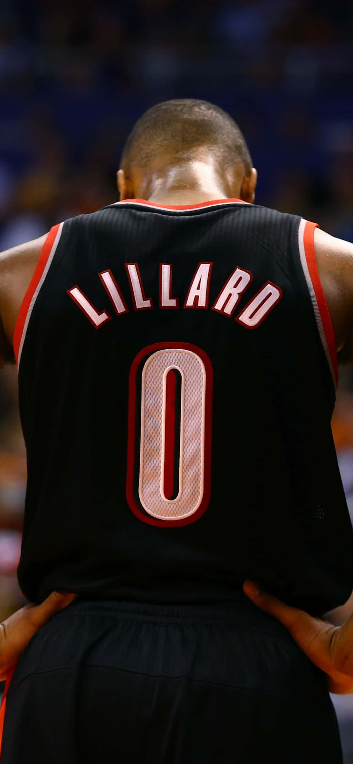 iPhone Xs Basketball 桌布 壁紙 — 籃球運動員 Damian Lillard 身穿黑色零號球衣站在球場上的背面照。