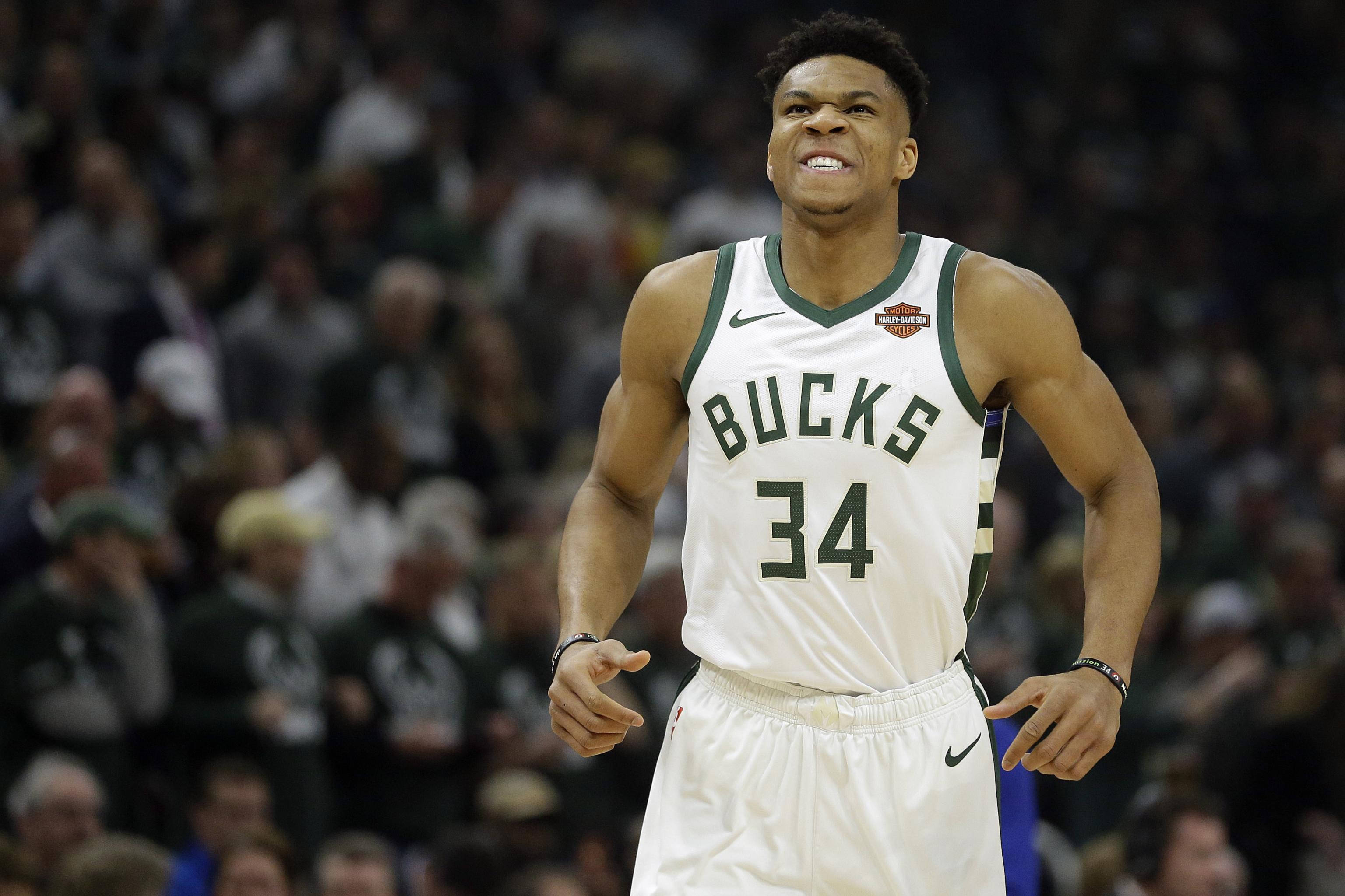 Giannis 桌布 壁紙 — 籃球運動員 Giannis Antetokounmpo 身穿密爾瓦基公鹿隊 34 號球衣，在比賽中熱烈慶祝，背景有觀眾。